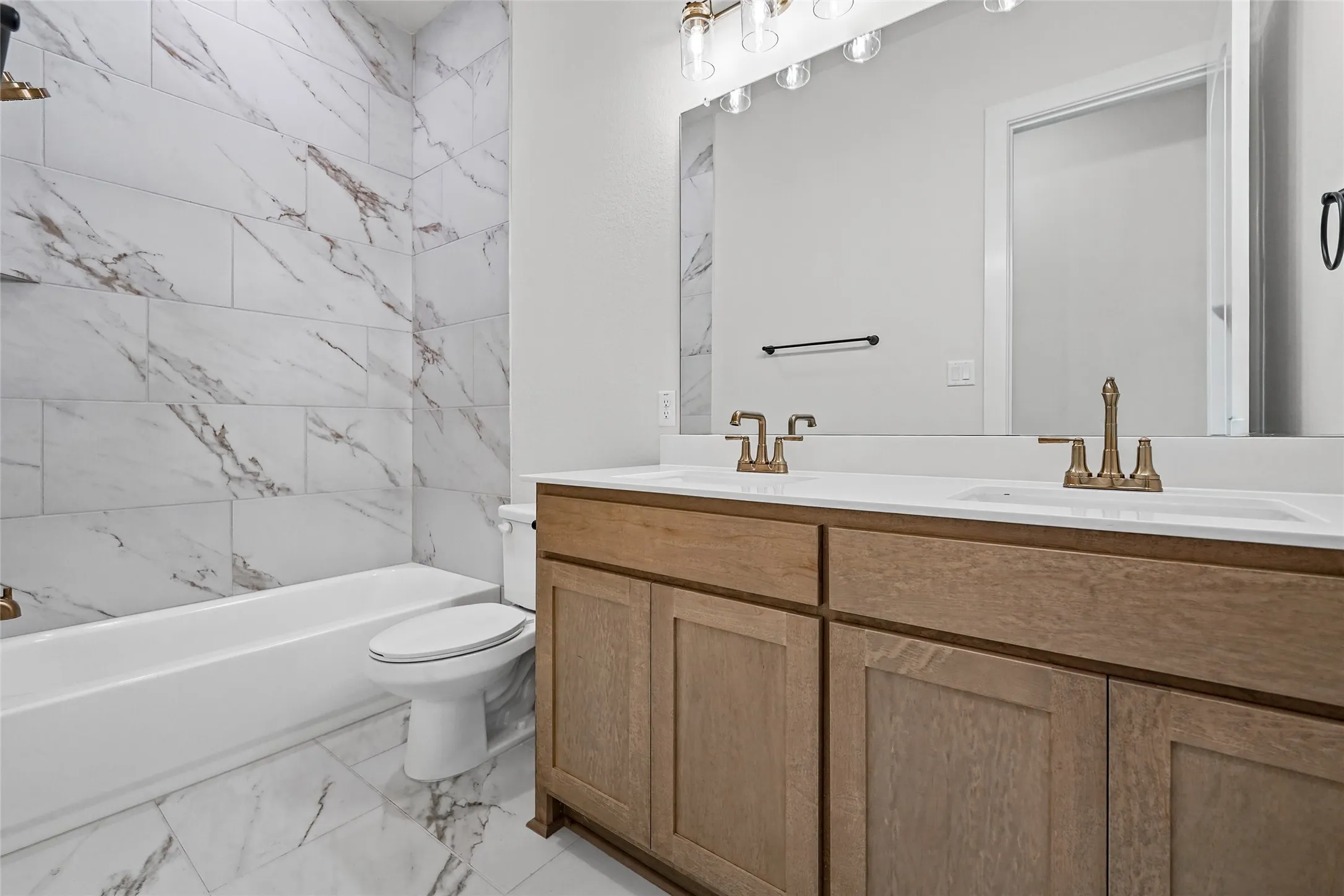 Dual vanity with bronze-finish fixtures, white countertops, and wood-finish cabinetry