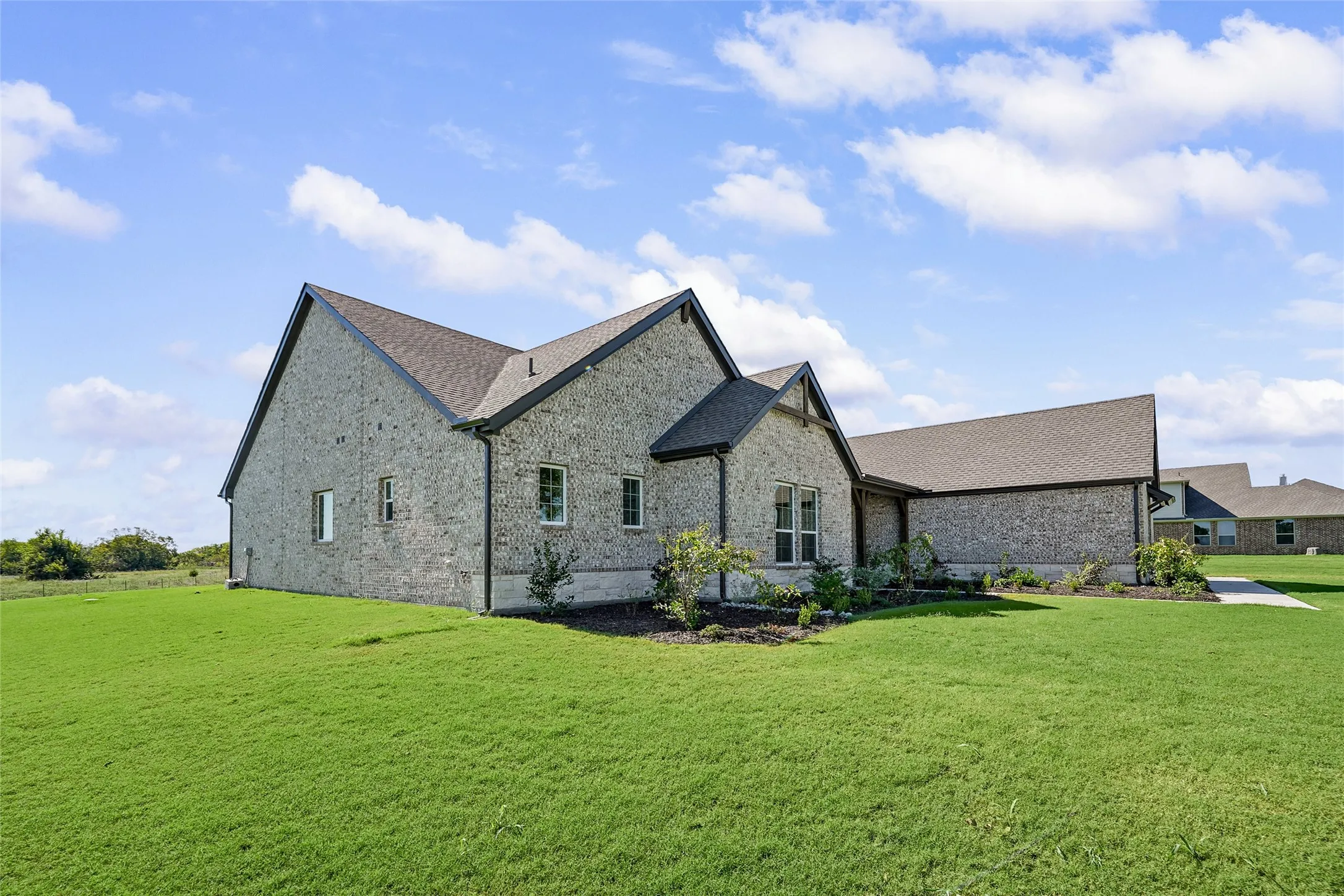 Brick exterior with dark trim accents, gabled rooflines, and a well-maintained lawn