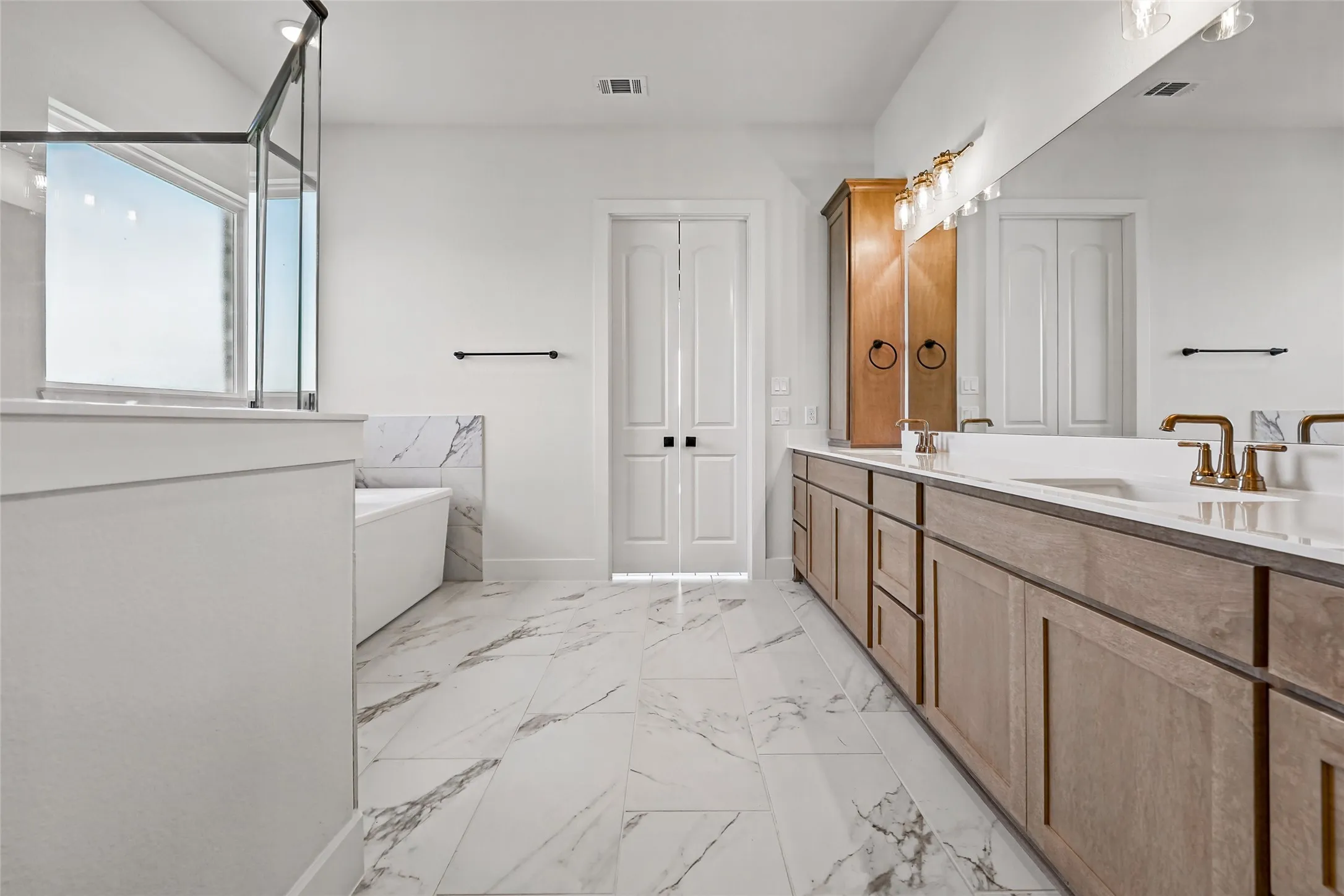 Dual vanity with light wood-finish cabinetry and bronze-finish fixtures