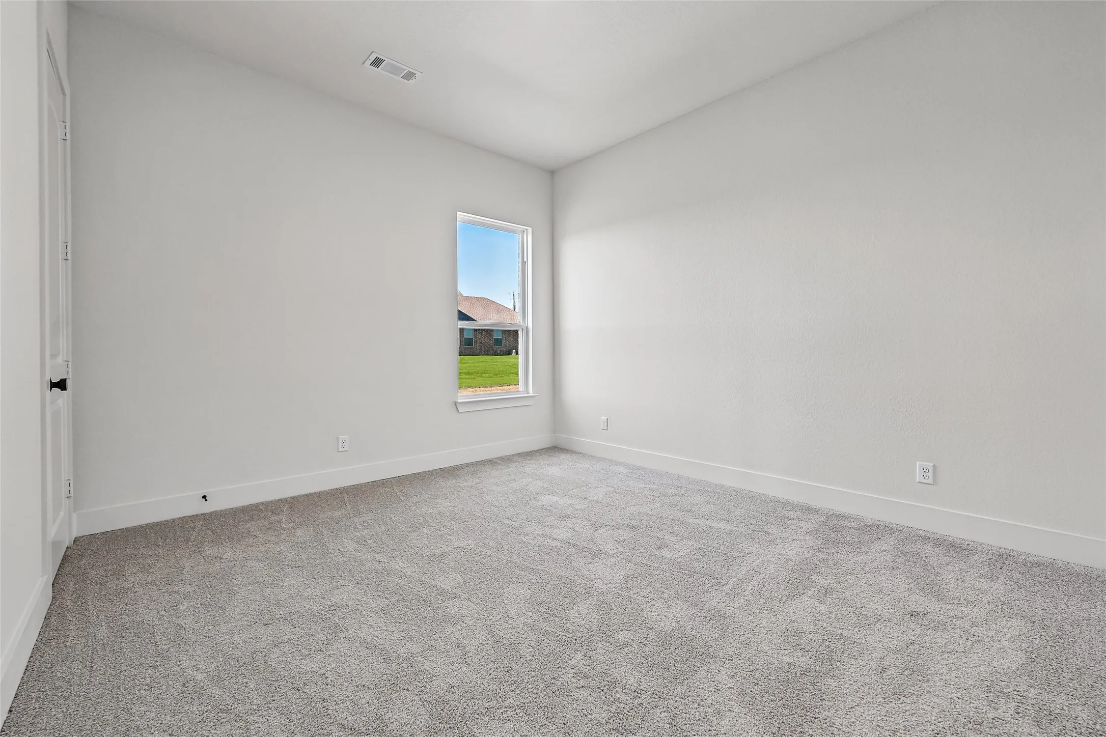 Neutral-toned wall finishes, light gray carpeting, and a single window offering natural illumination