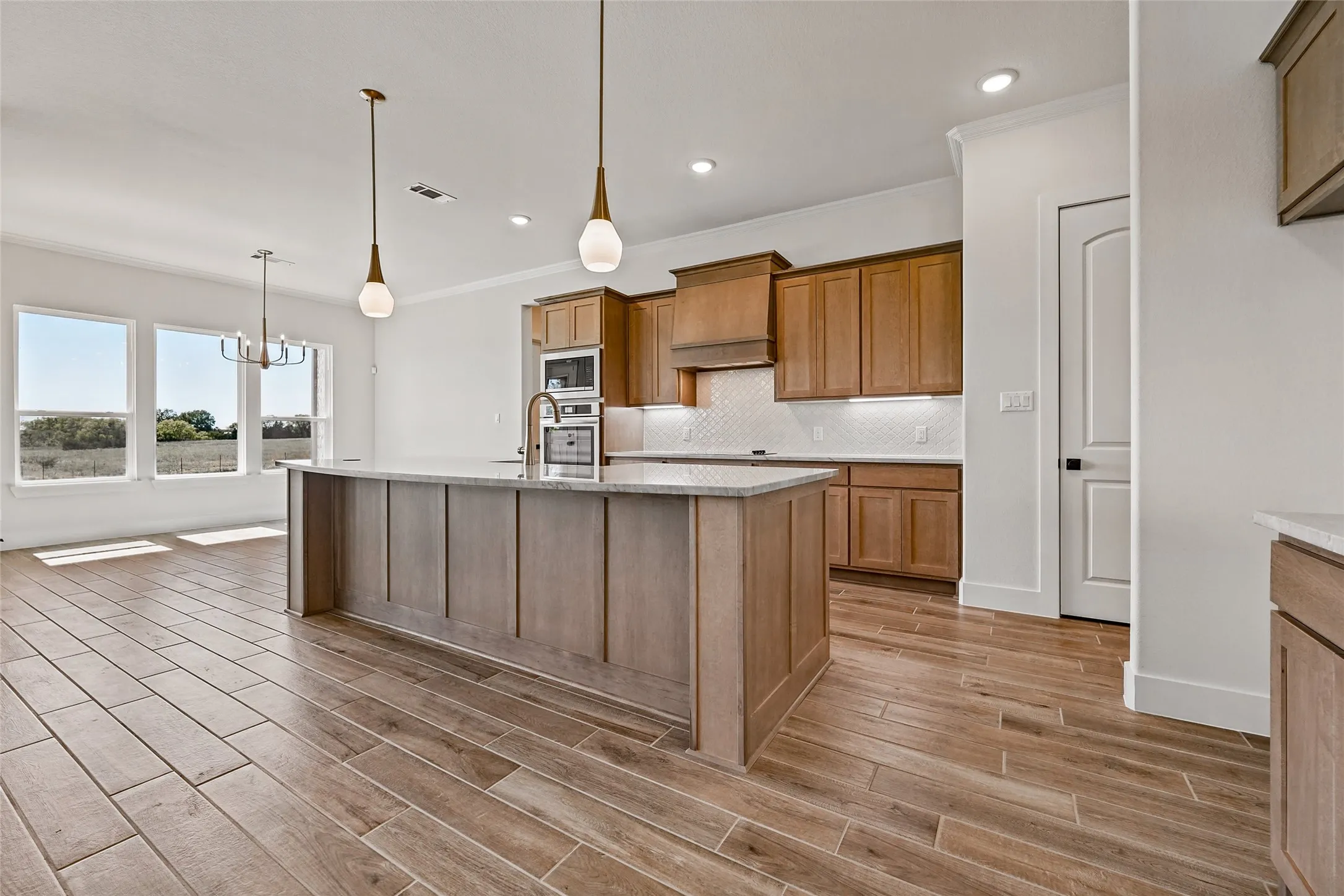 Gourmet kitchen with light wood-finish cabinetry, stainless steel appliances, and a central island with a light-toned countertop