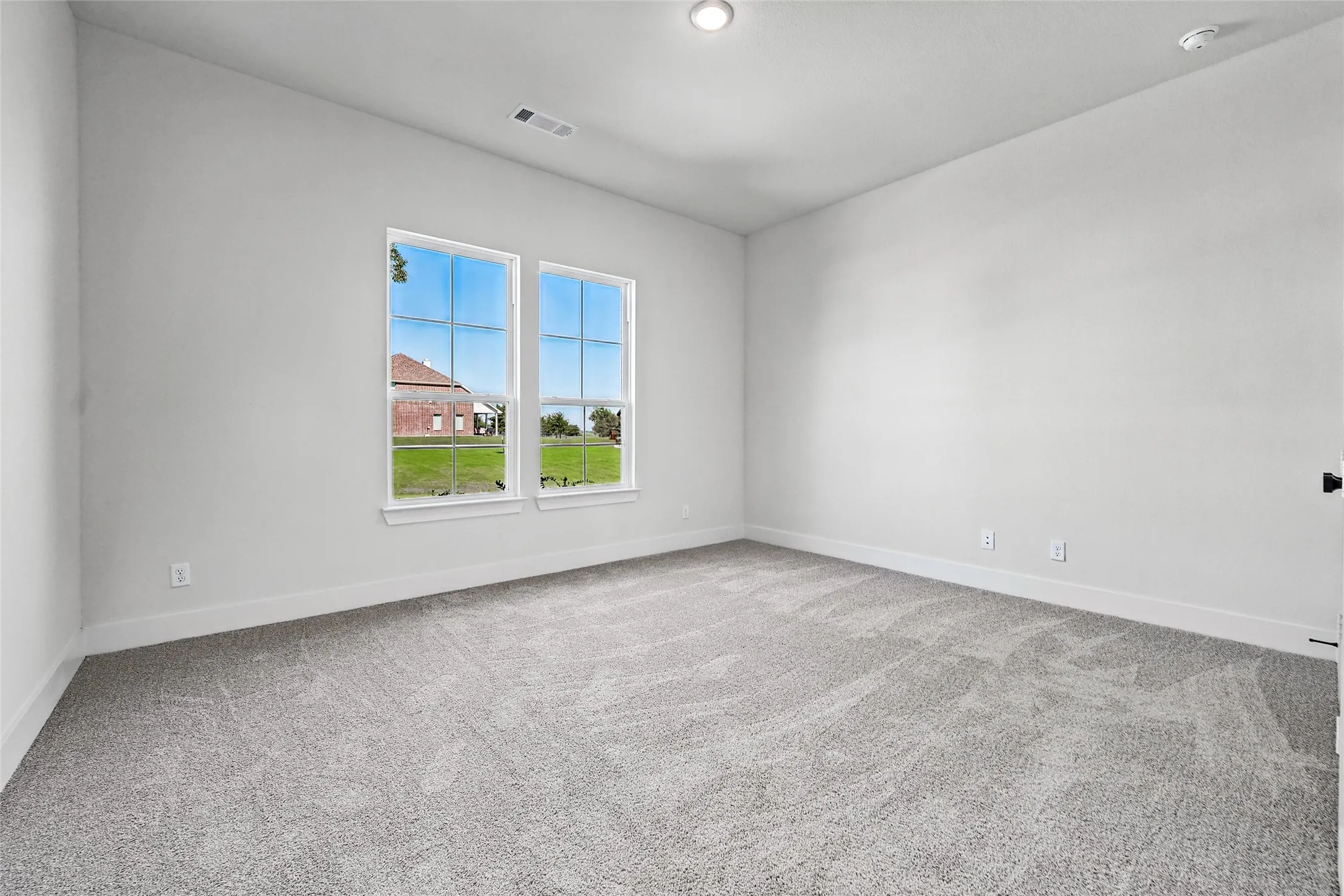 Wall-to-wall carpeting, dual windows, recessed ceiling lighting, and a neutral color palette