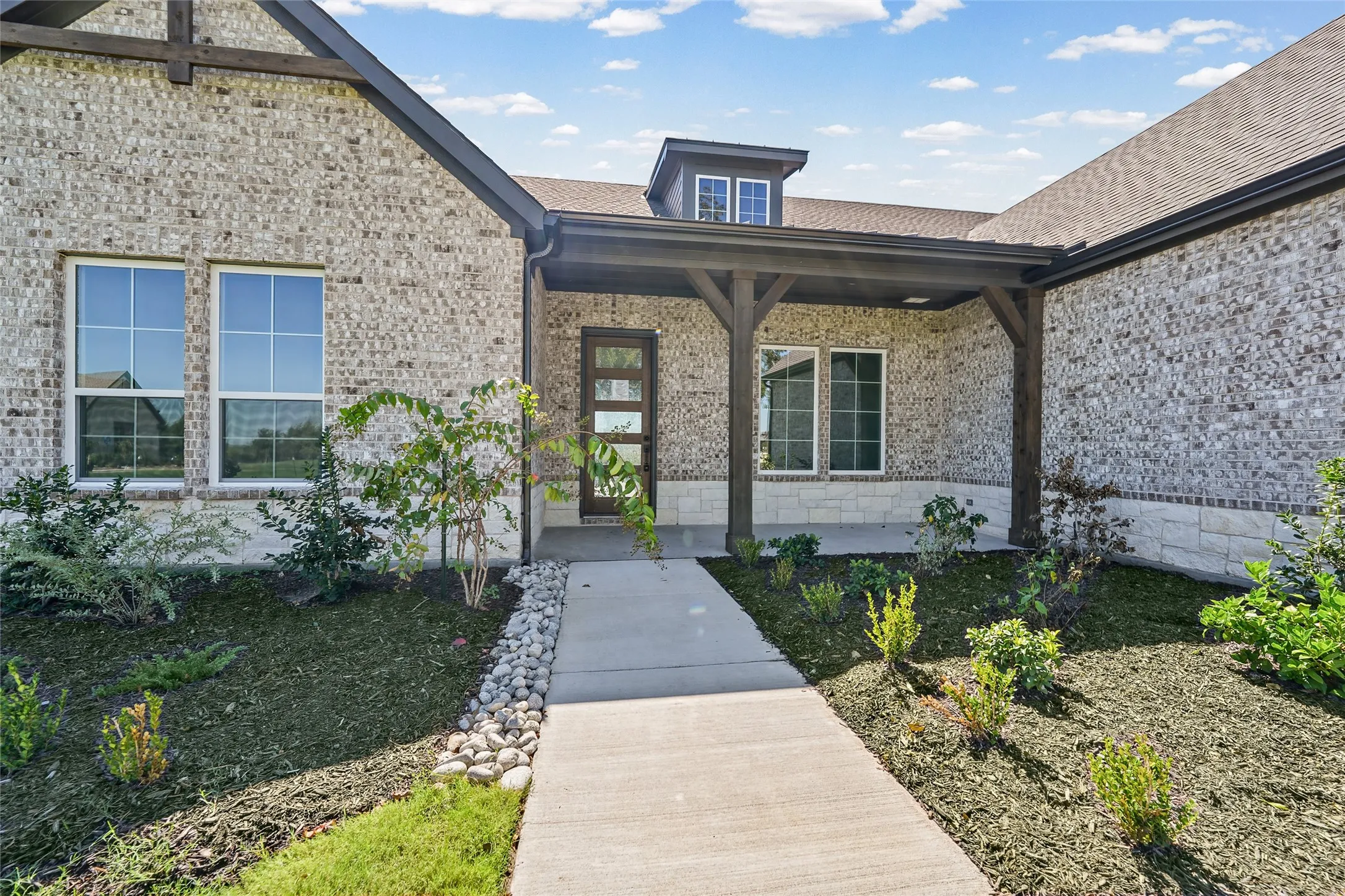 Brick exterior with stone accents, covered entry, and a dormer window