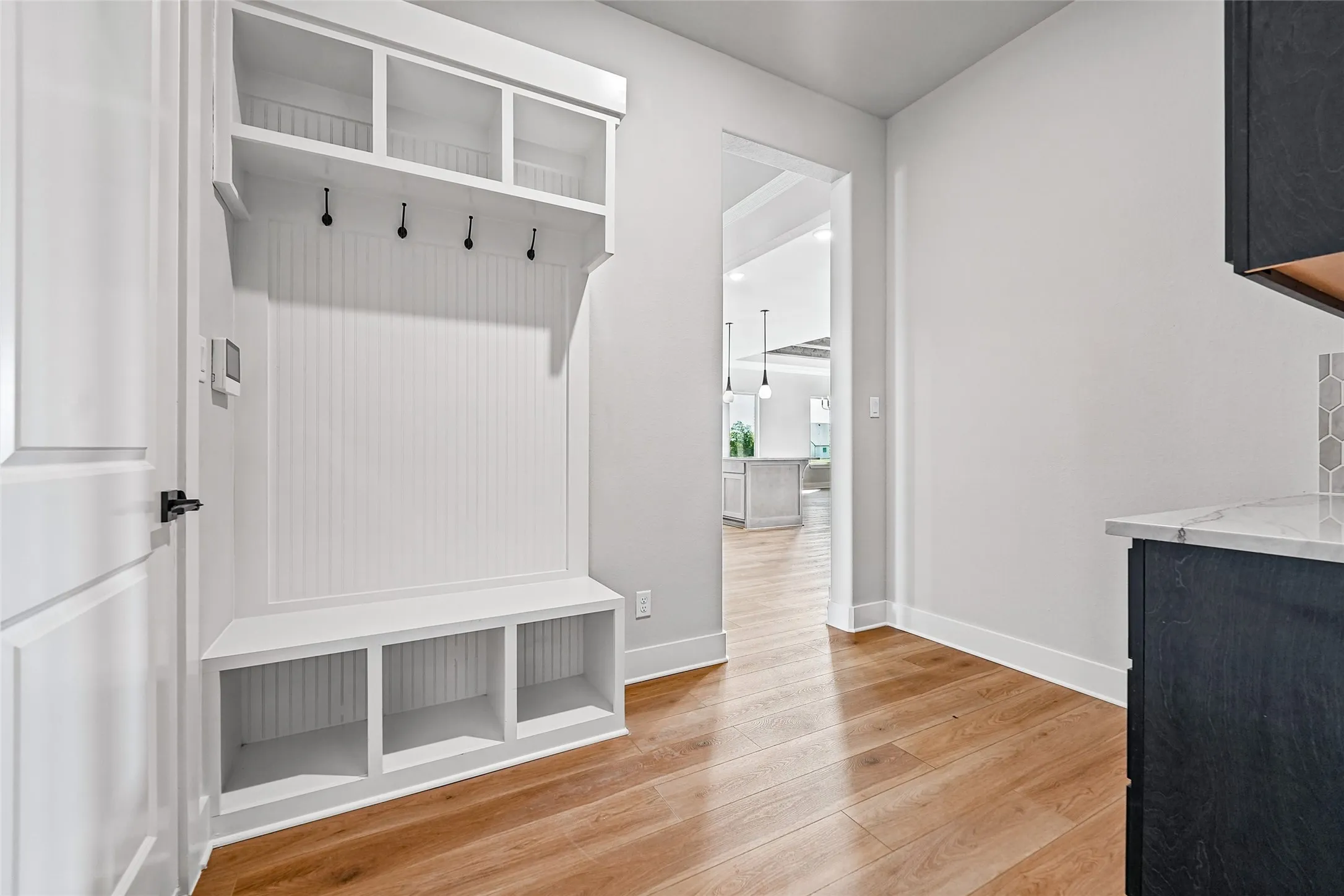 Built-in storage bench with overhead shelving, beadboard backing, and black hooks