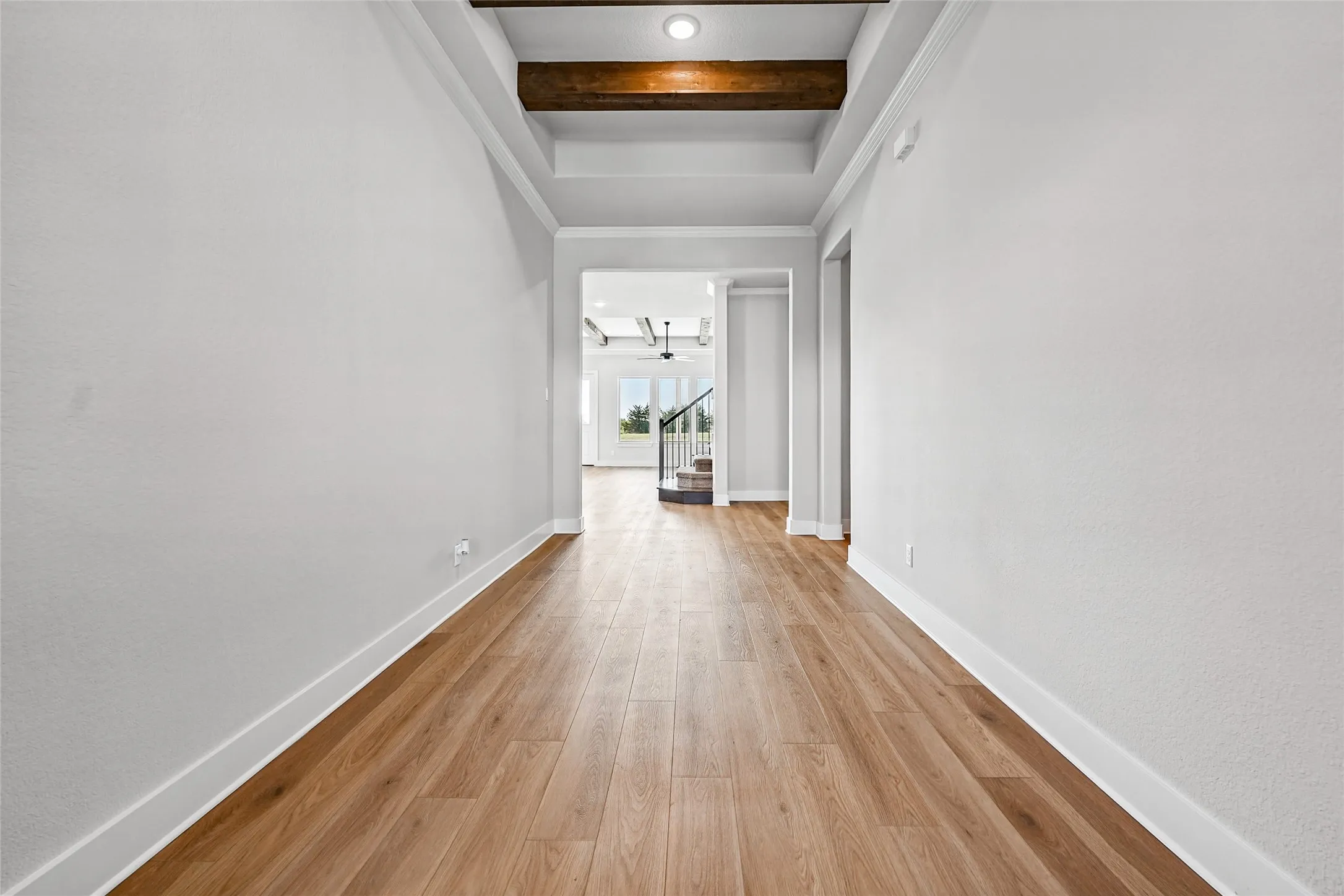 Wood-finish flooring, recessed lighting, white walls, and a tray ceiling with exposed wood beams