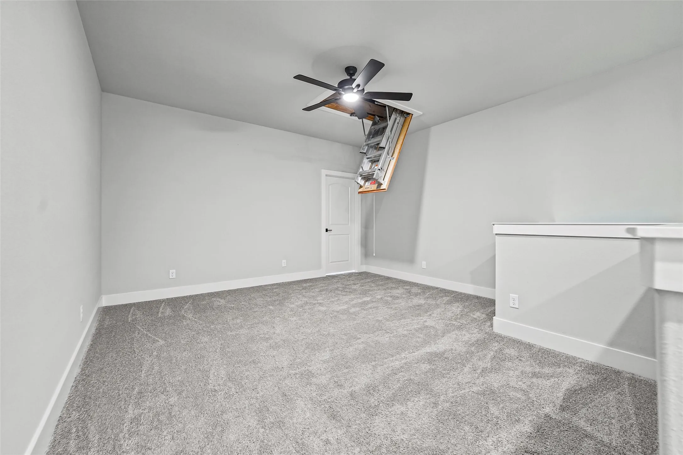 Spacious room with gray carpet, a ceiling fan, and a white interior door