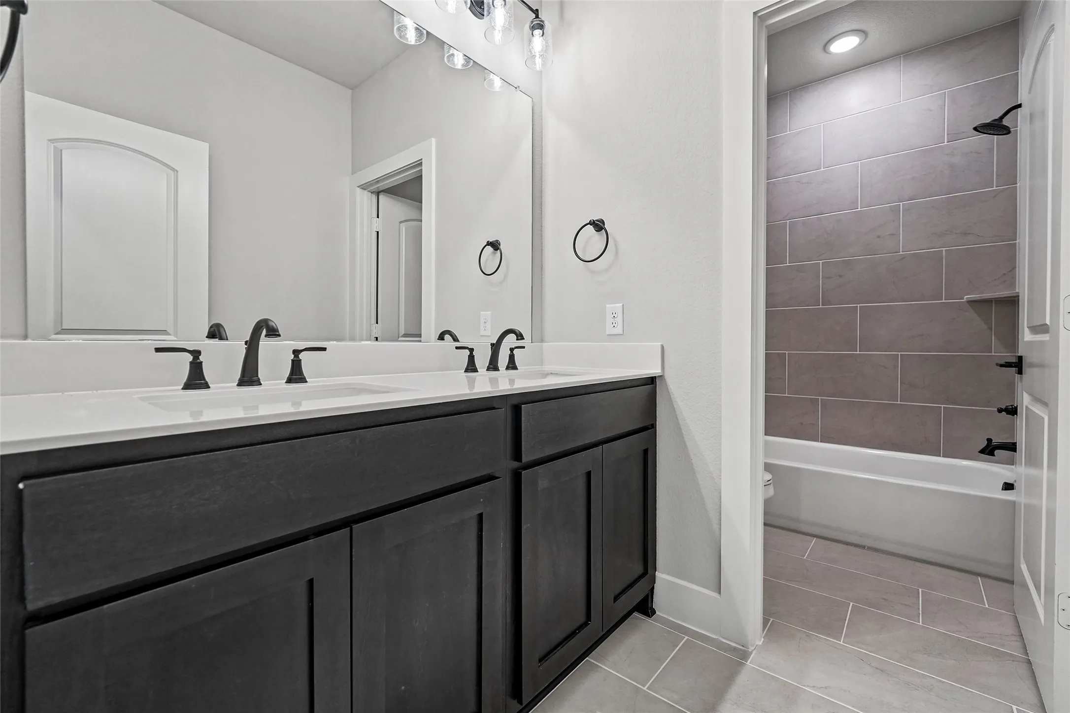 Dual sink vanity with dark wood-finish cabinetry and light-toned countertops