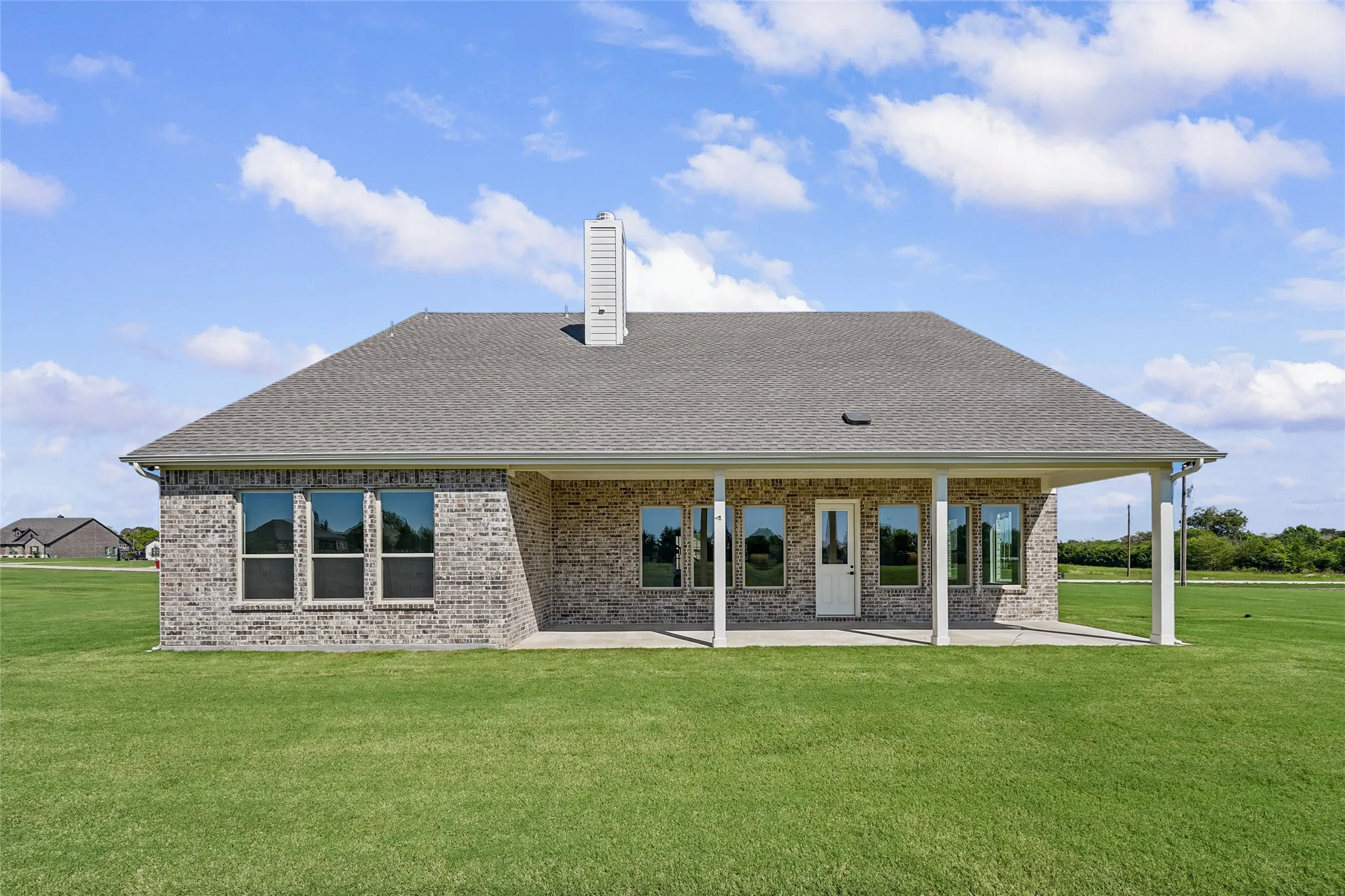Brick exterior with a gray shingle roof and a covered patio