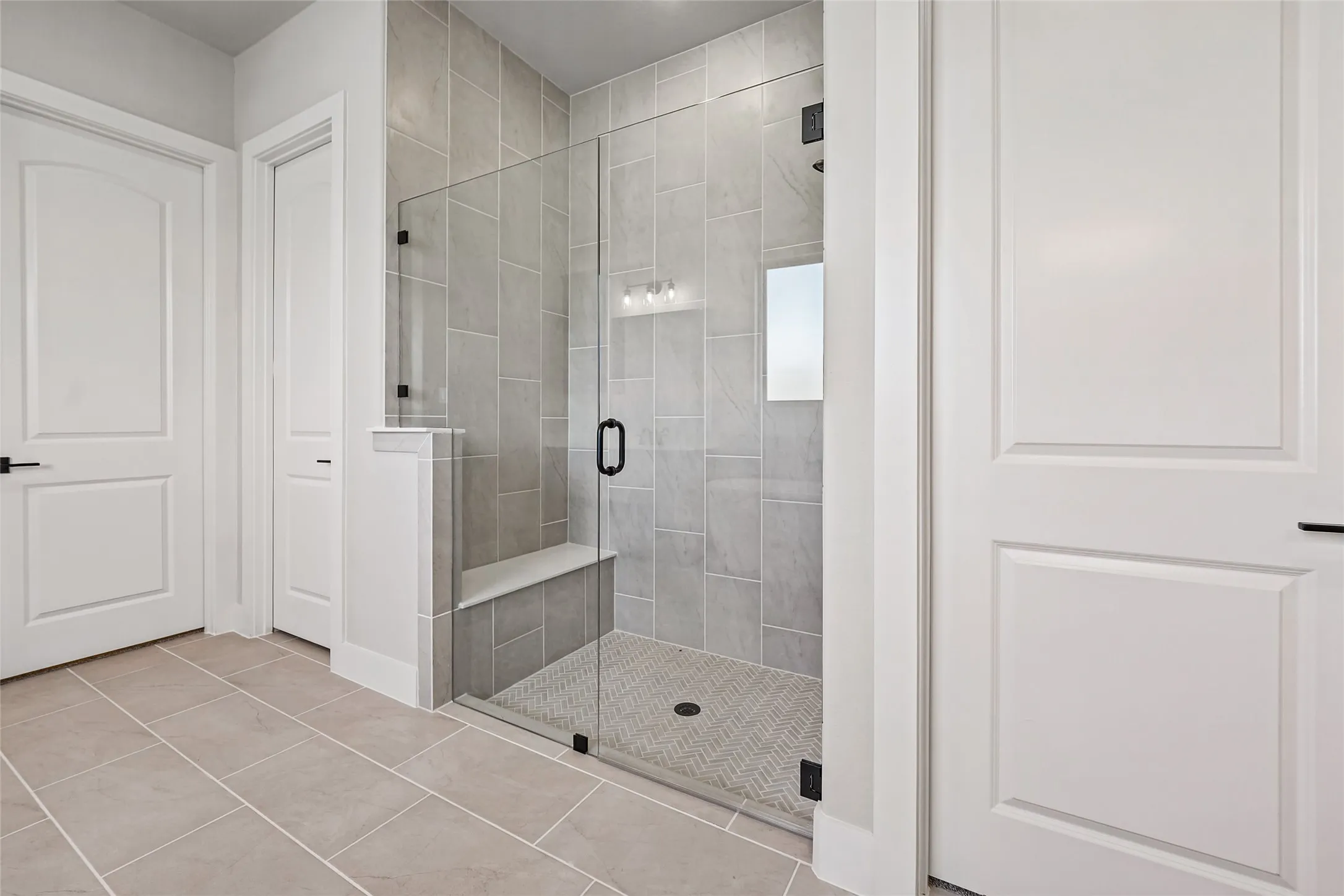 Spacious walk-in shower with clear glass enclosure and built-in bench