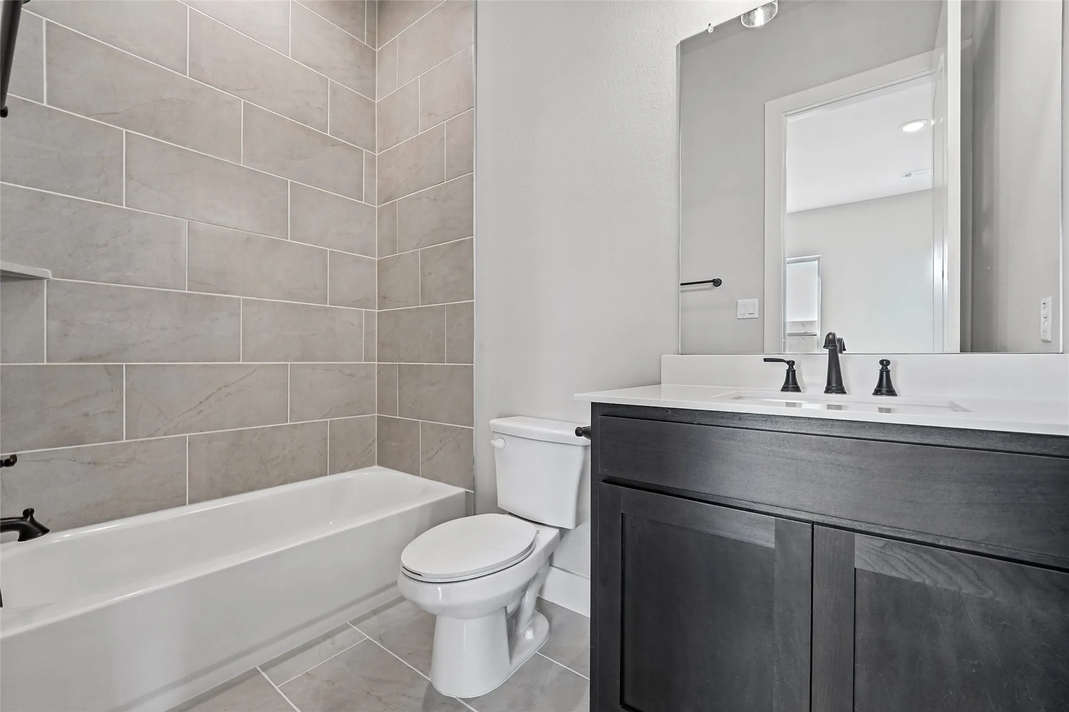Bathroom with a dark wood-finish vanity, white countertop, and rectangular sink