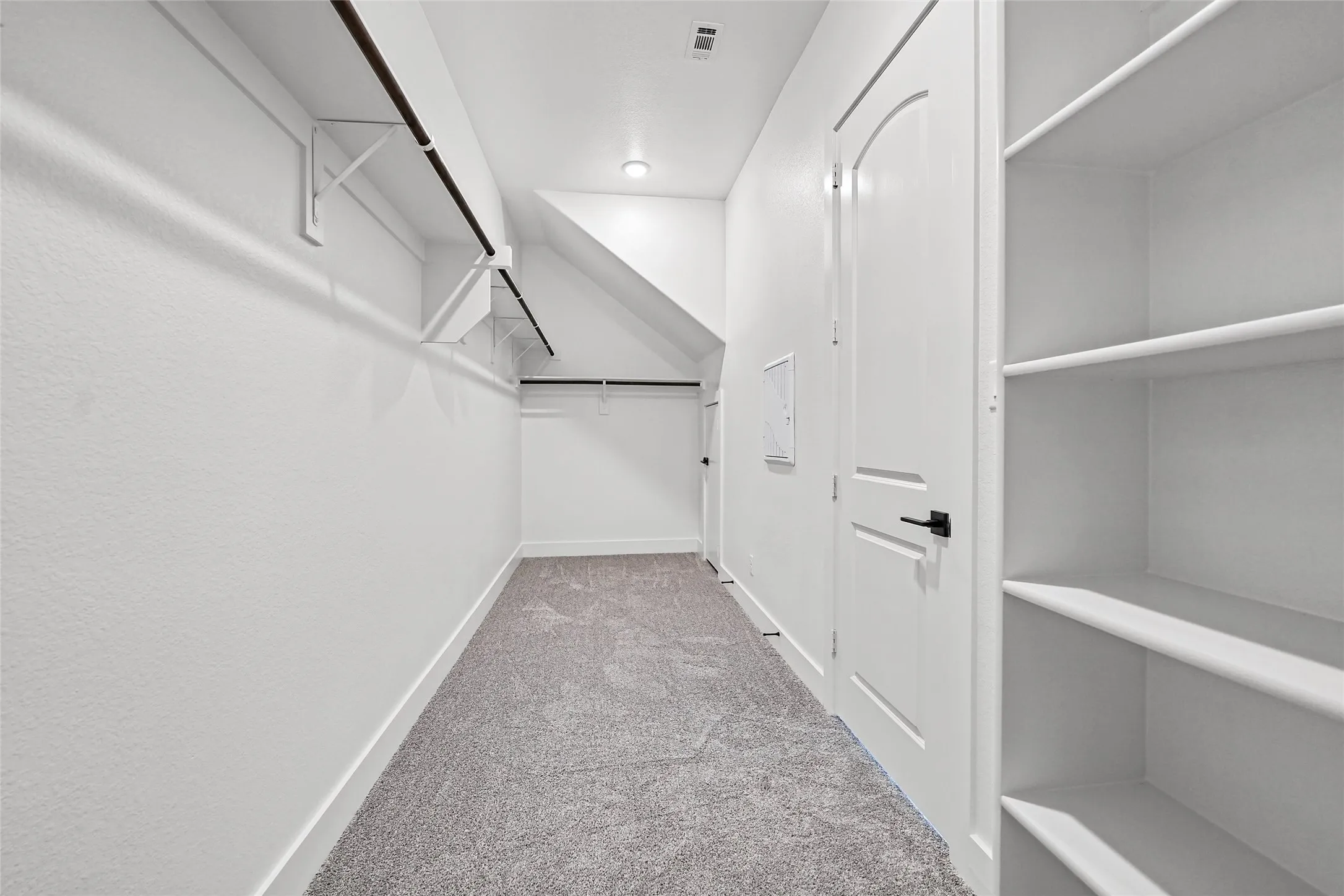 Built-in shelving, hanging rods, recessed lighting, and gray carpet flooring