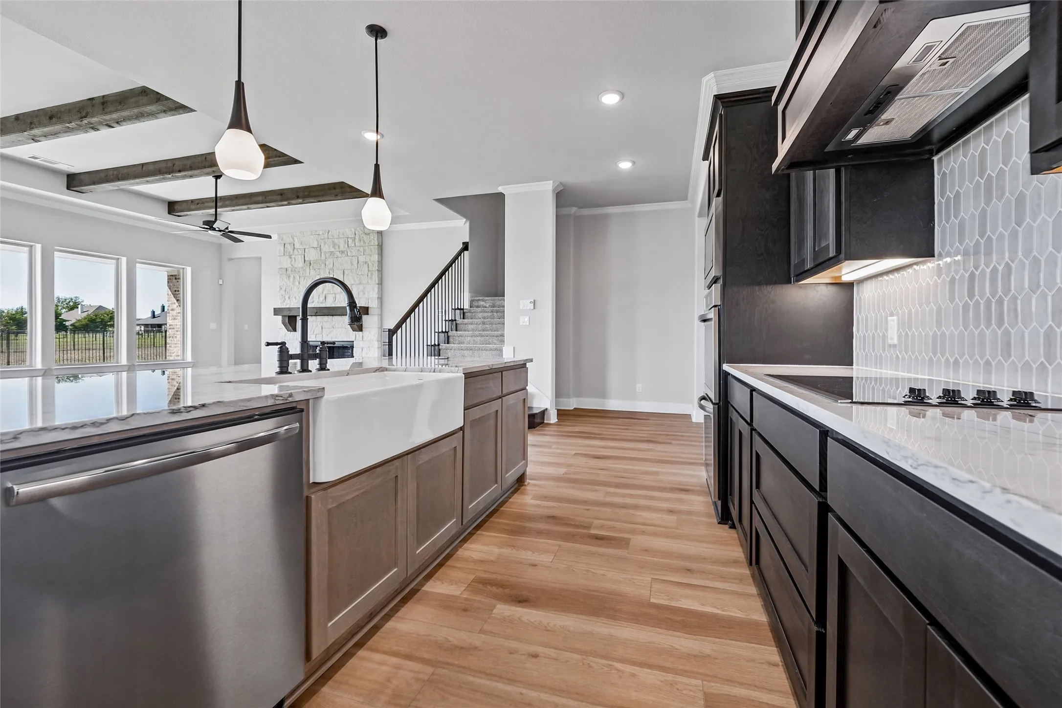 Gourmet kitchen featuring a large island, wood-finish flooring, dark cabinetry, and a hexagon tile backsplash