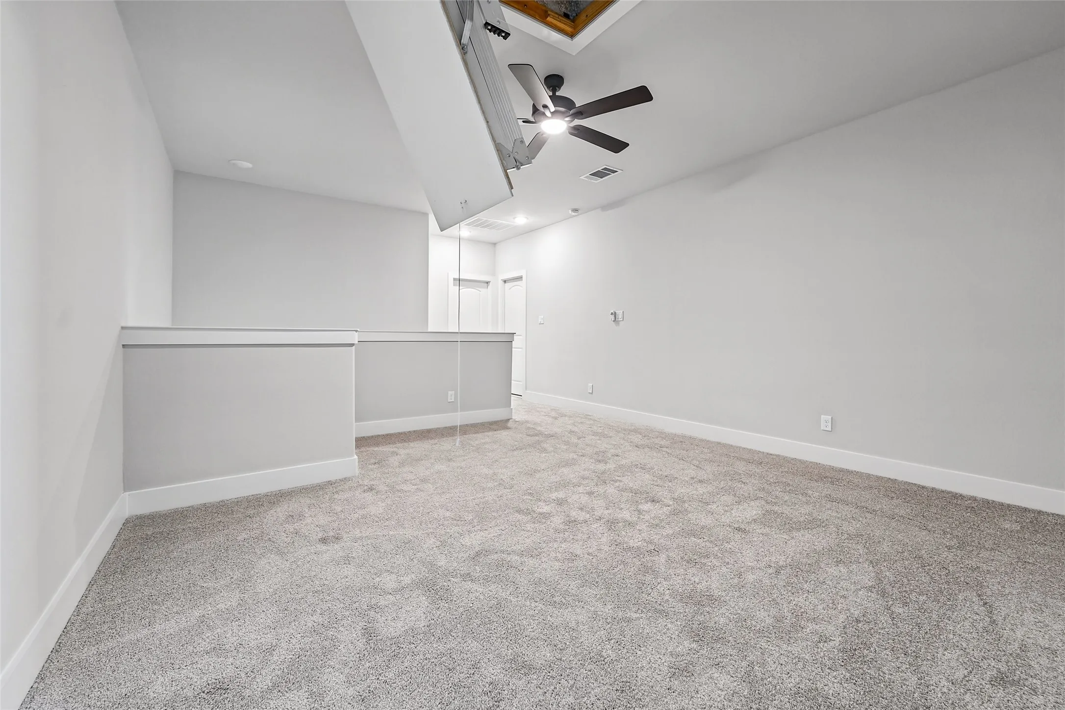 Expansive loft space with gray carpeting, white walls, a ceiling fan, and recessed lighting