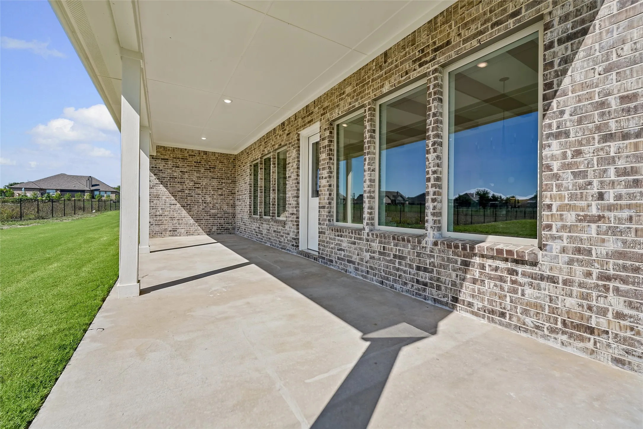 Covered concrete patio featuring recessed lighting, a brick exterior, and multiple large windows