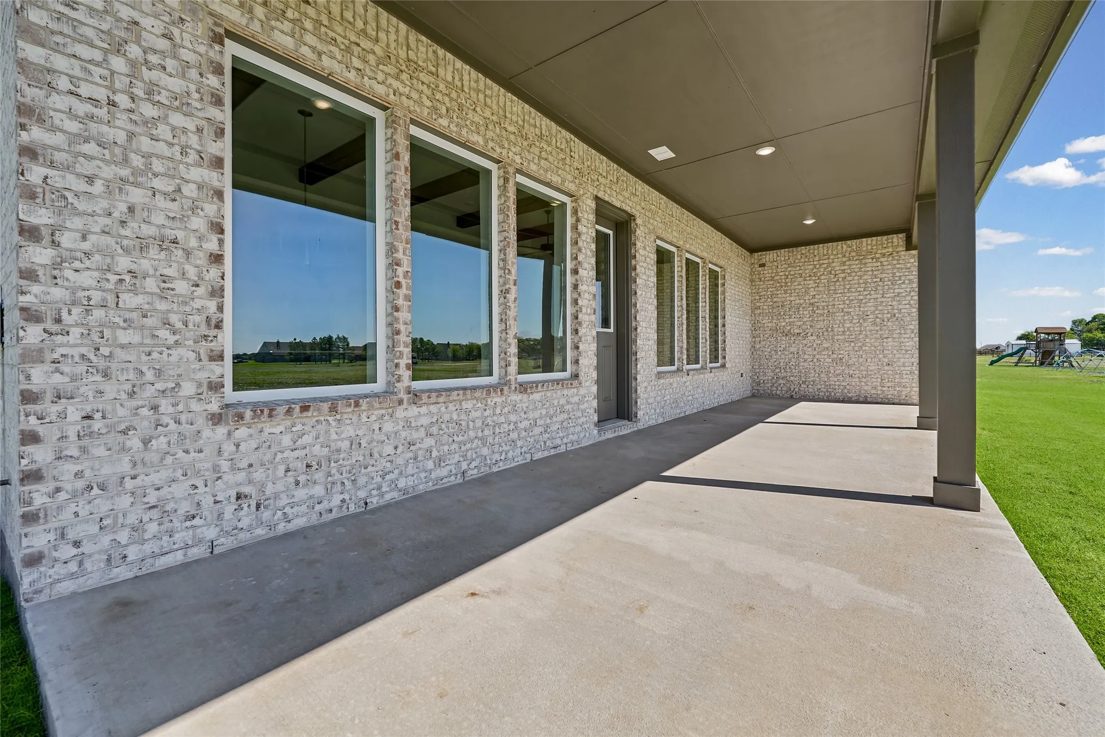Covered patio with recessed lighting, supported by columns, offering direct access to the exterior through a glass-paneled door