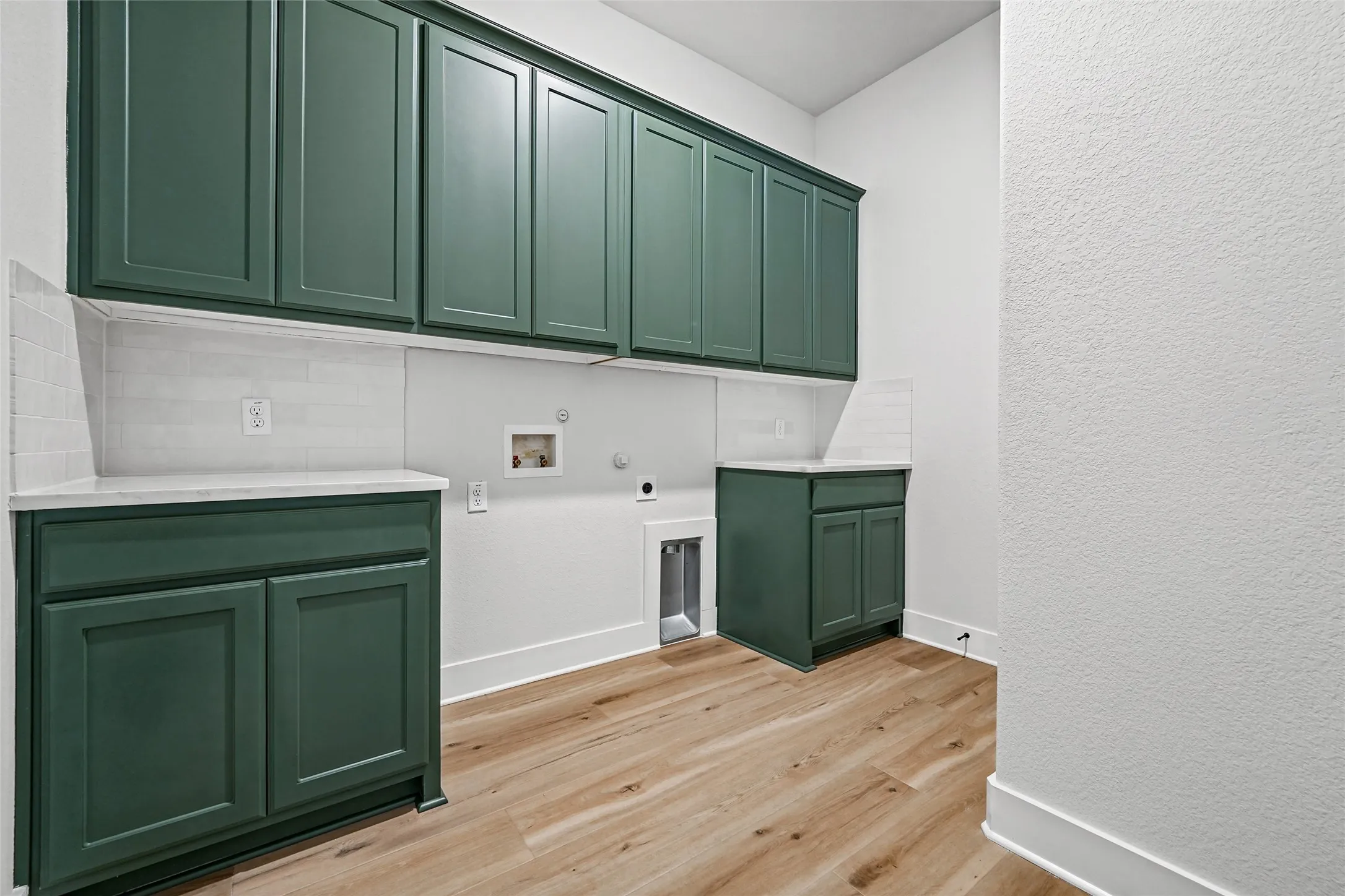 Green cabinetry with white countertops, white subway tile backsplash, and wood-finish flooring
