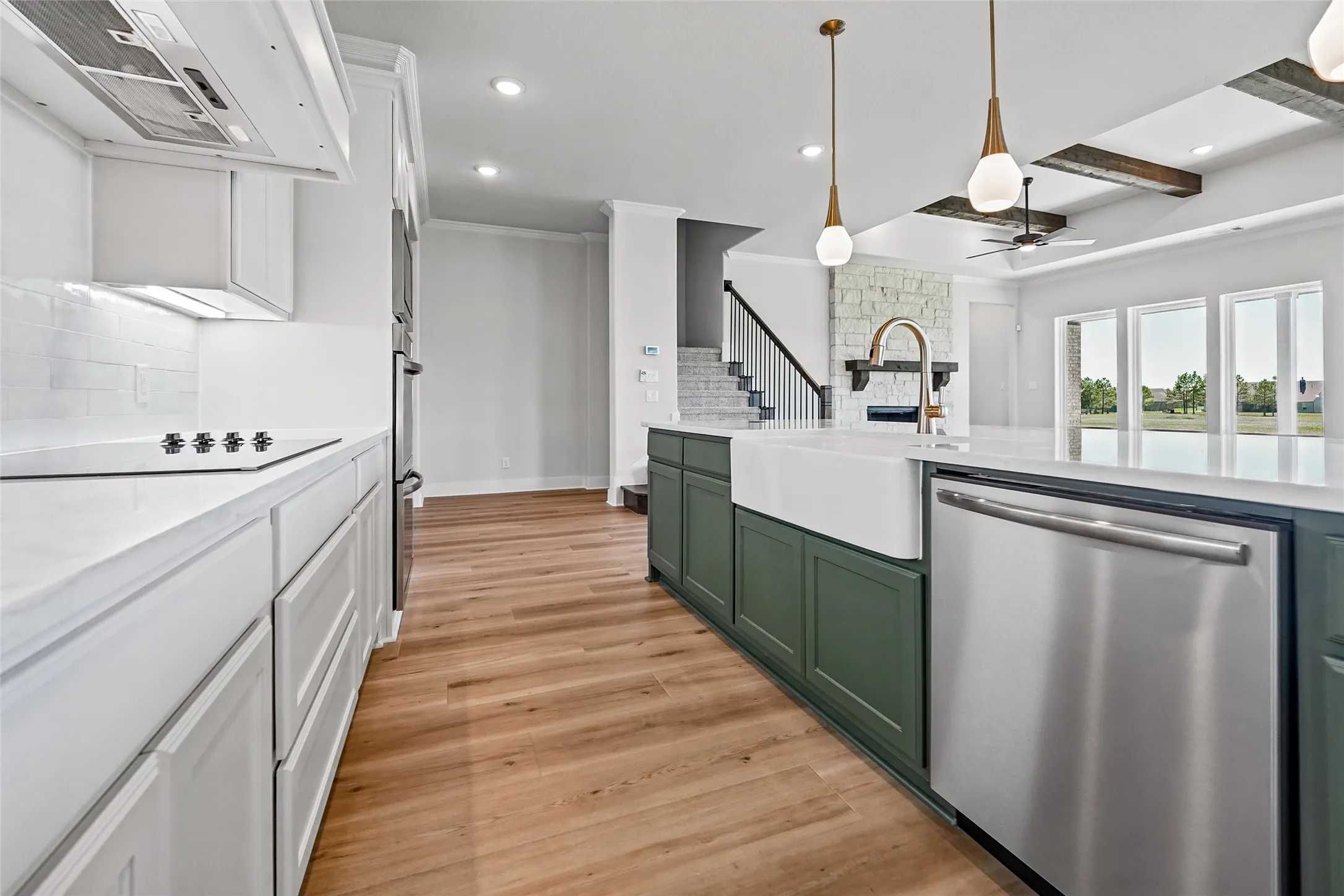 Gourmet kitchen featuring a built-in cooktop, double wall ovens, wood-finish flooring, a farmhouse sink, and stainless steel appliances