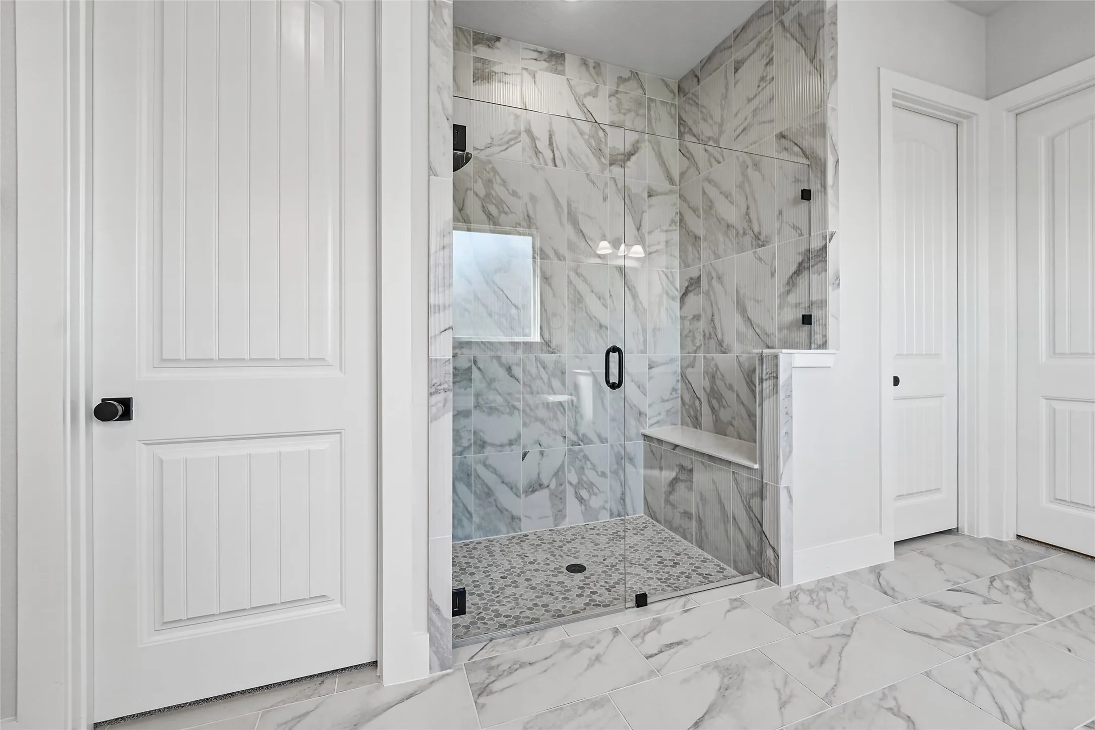 Spacious walk-in shower with clear glass enclosure and black hardware
