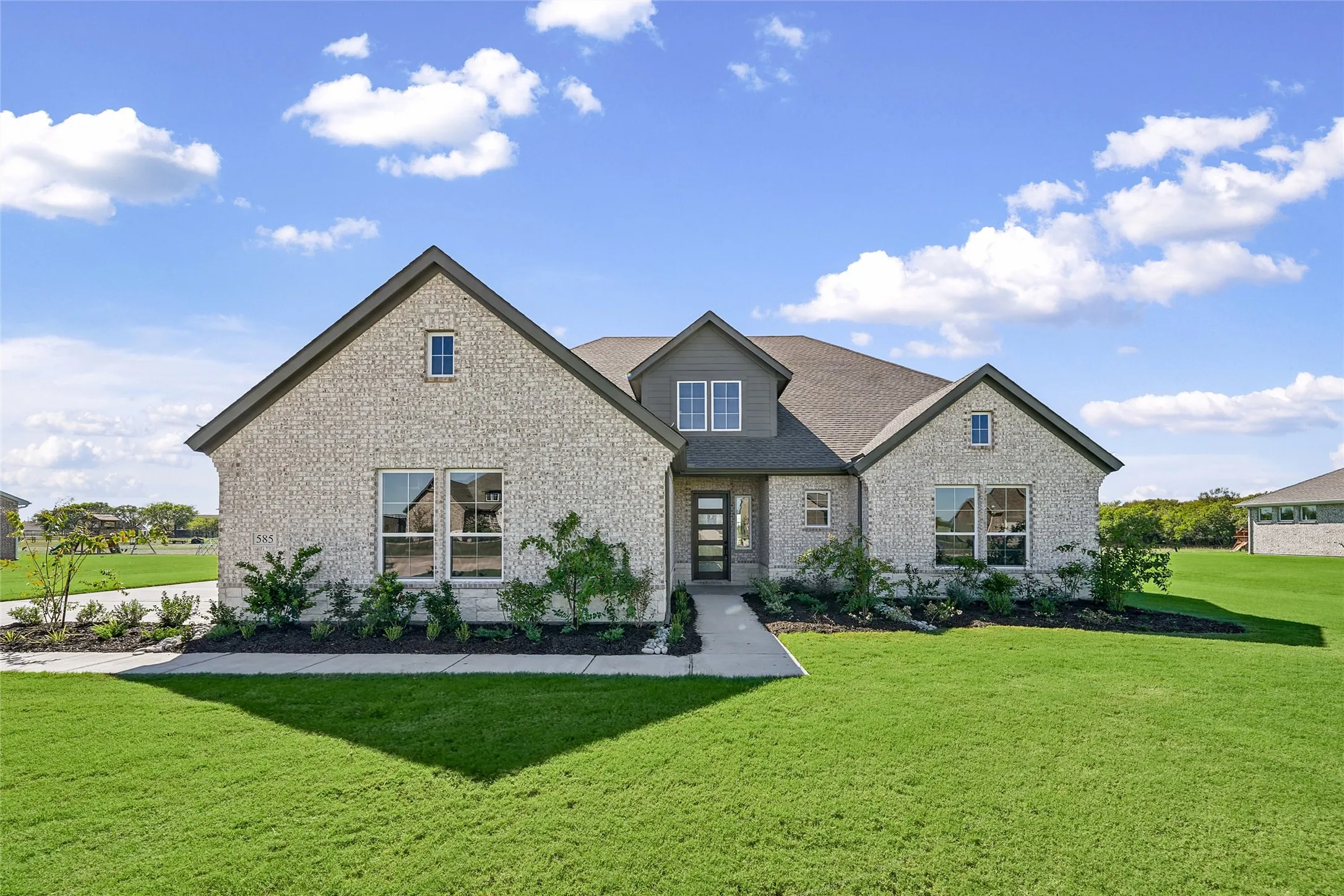 Modern-style residence featuring a light-colored brick exterior and dark gray shingle roof