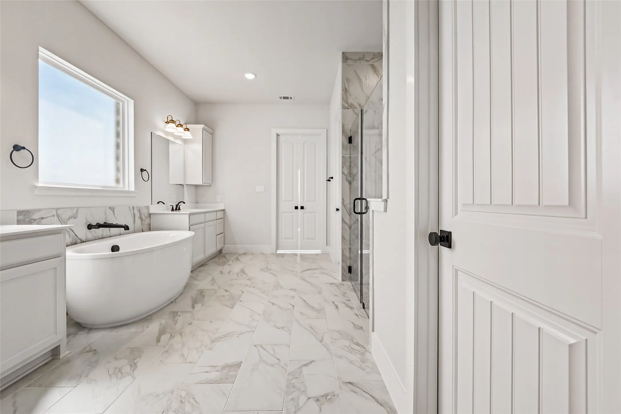Freestanding soaking tub with wall-mounted fixtures