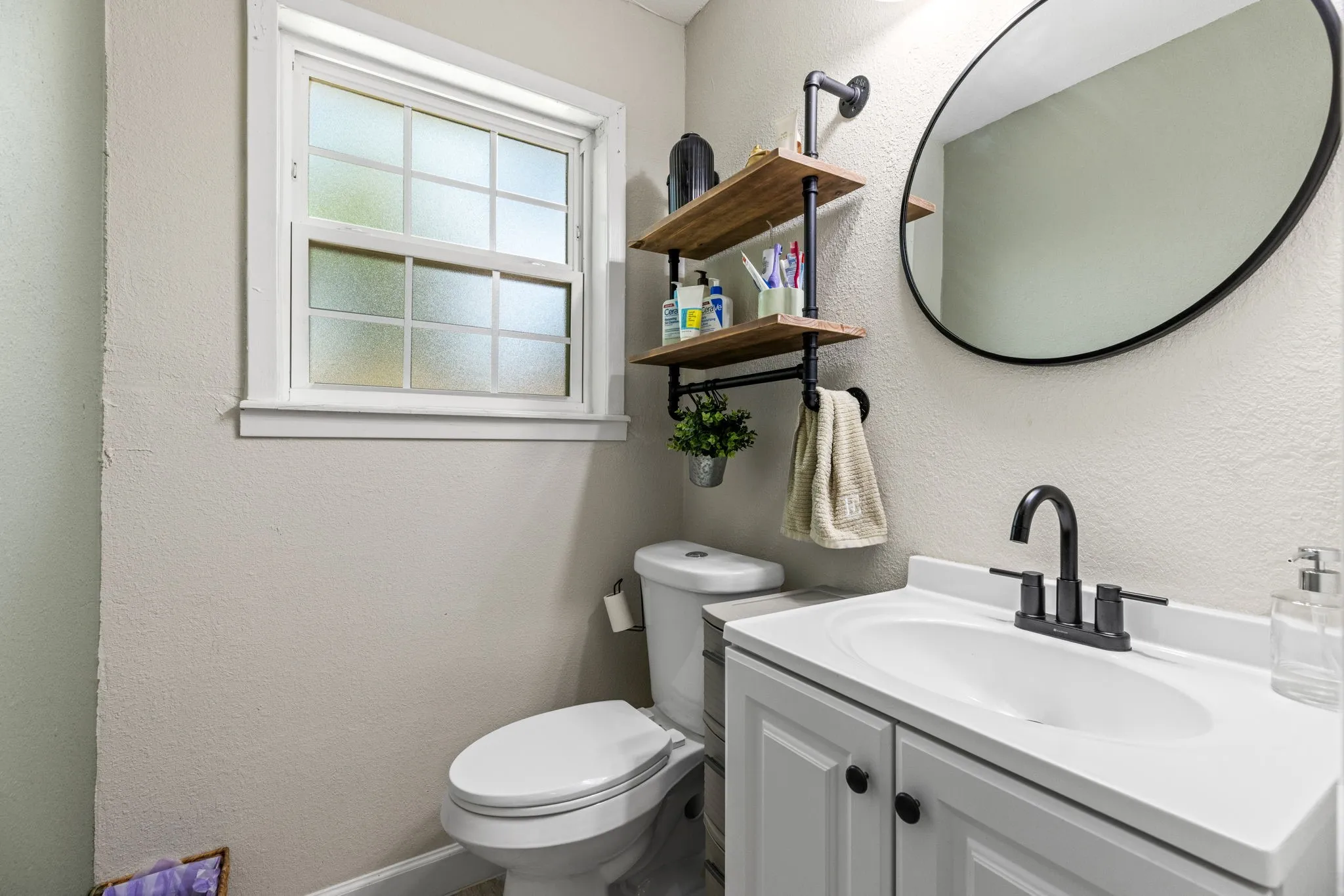 Contemporary bathroom vanity featuring a white countertop and basin, matte black faucet, and white cabinetry with black hardware