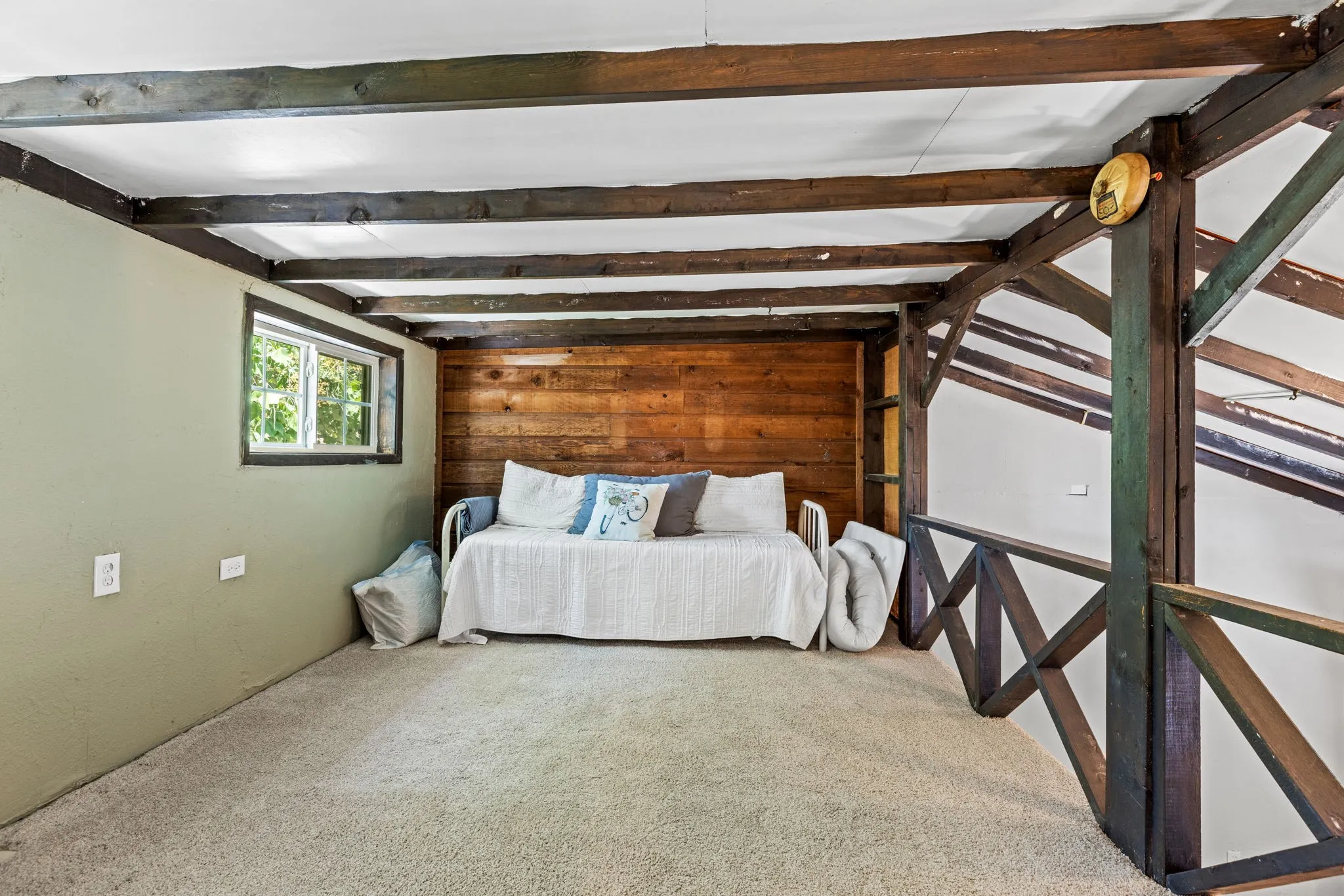 Loft space featuring exposed ceiling beams and a wooden accent wall