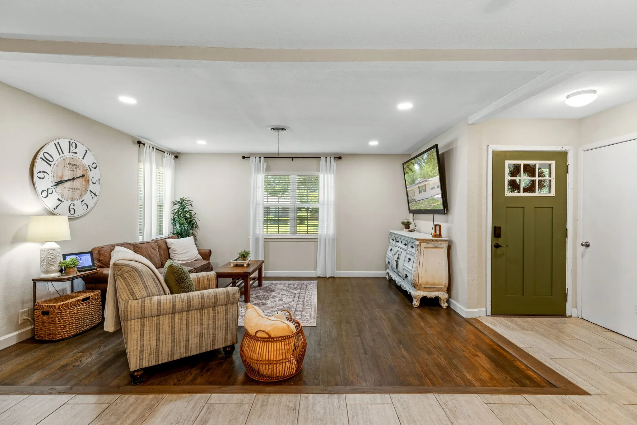 Open-concept living space featuring recessed lighting, wood-finish flooring, and a distinct front entry door with a window grid