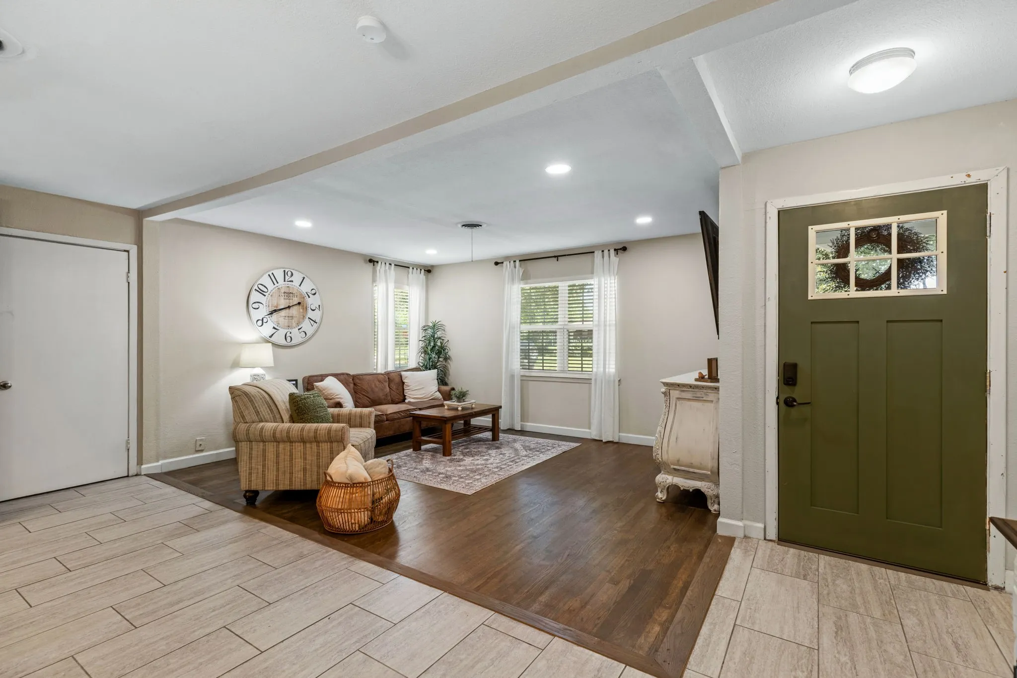 Entryway with a craftsman-style door featuring a window grid, complemented by wood-finish flooring in the living area and large format tile in the entry