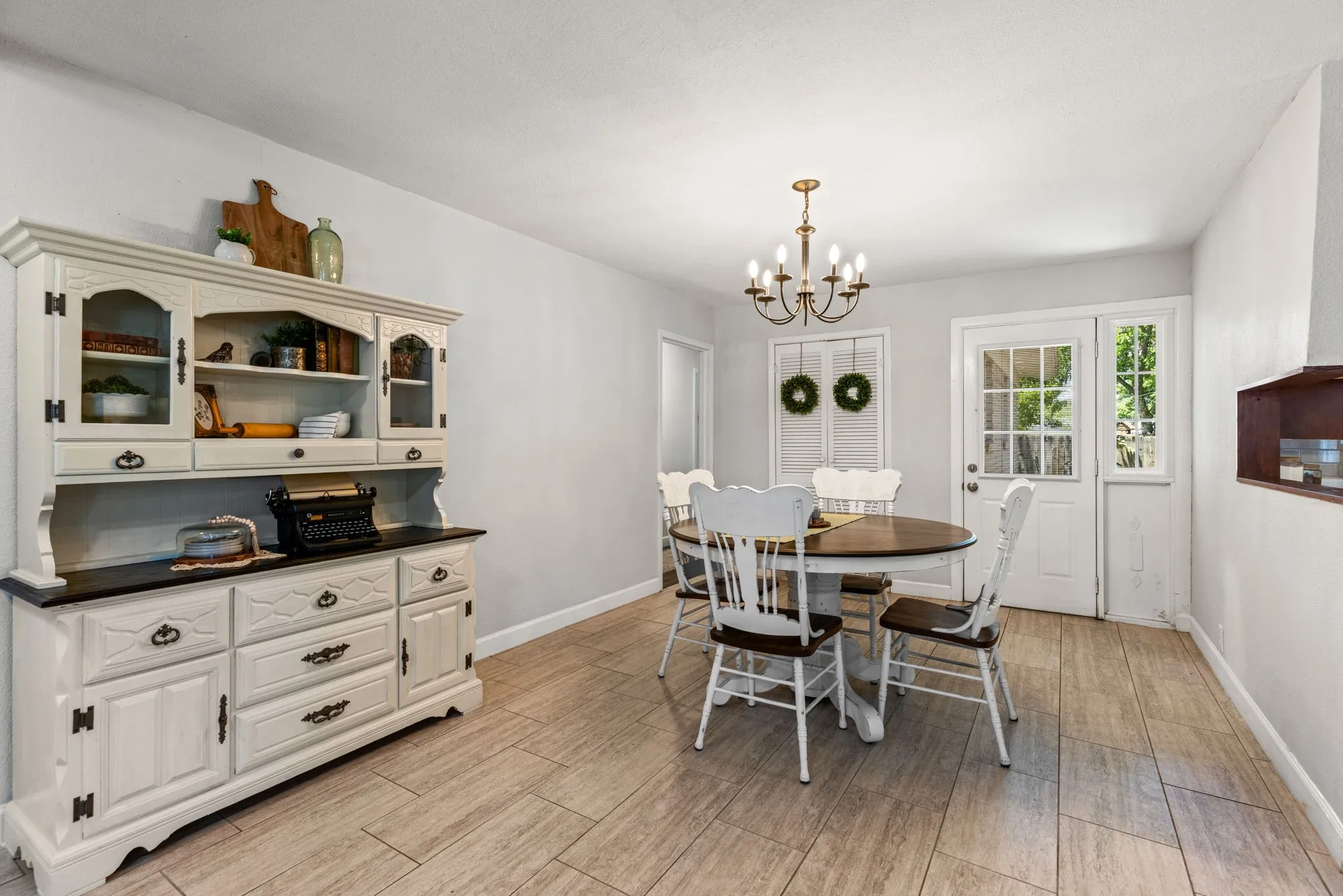 Dining area featuring wood-finish flooring, a multi-bulb chandelier, and a built-in wall unit