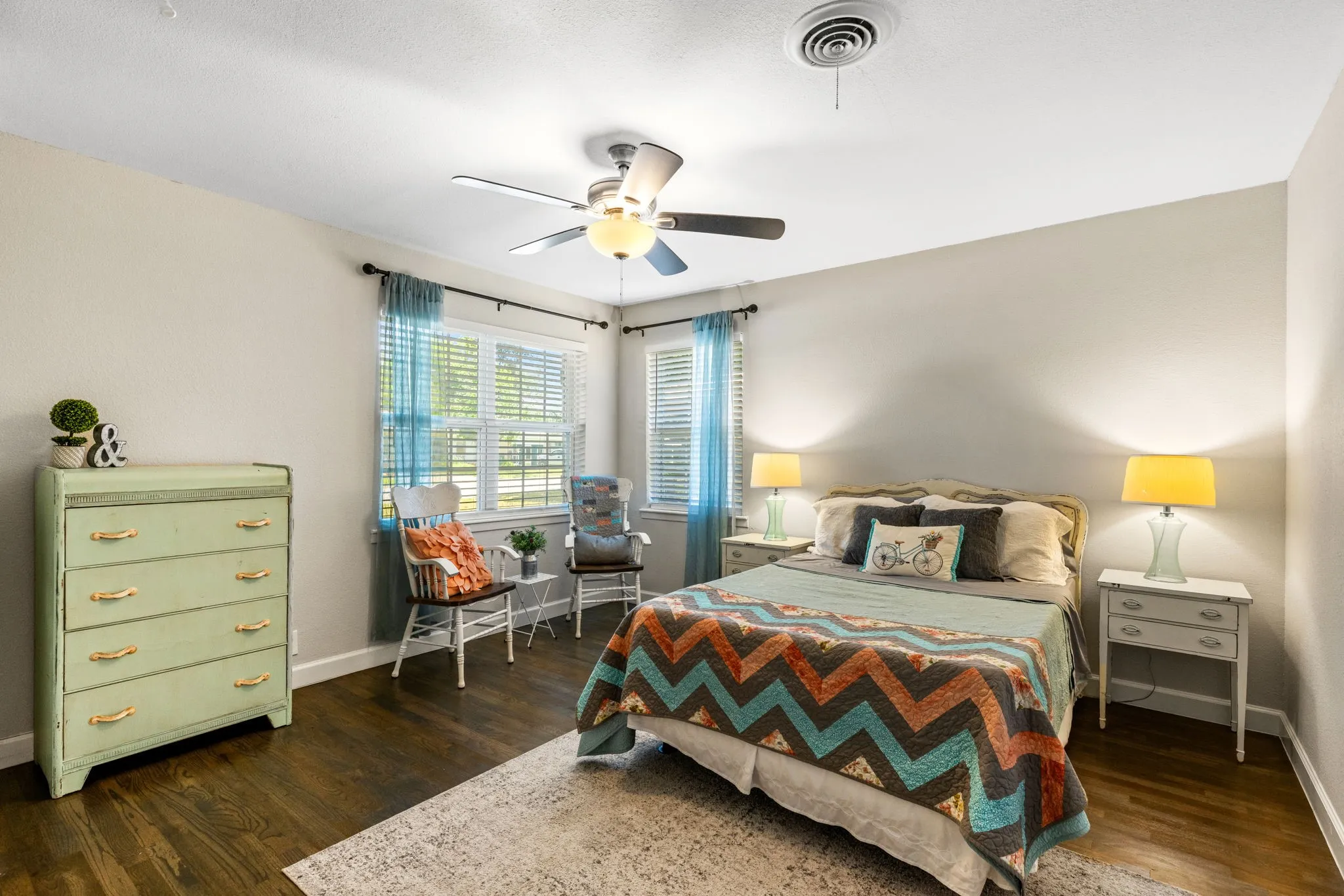 Spacious room featuring wood-finish flooring, light-toned walls, and a ceiling fan with integrated lighting