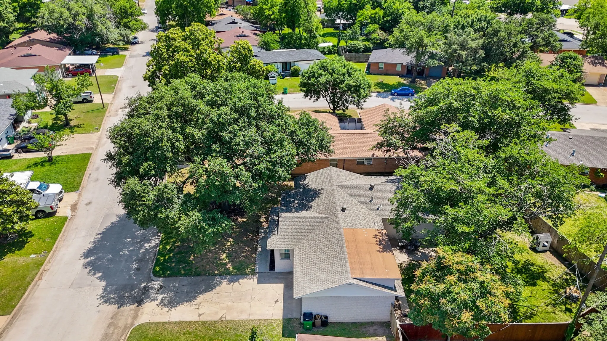 Aerial perspective showcasing the property's roofline, surrounding mature trees, and street presence