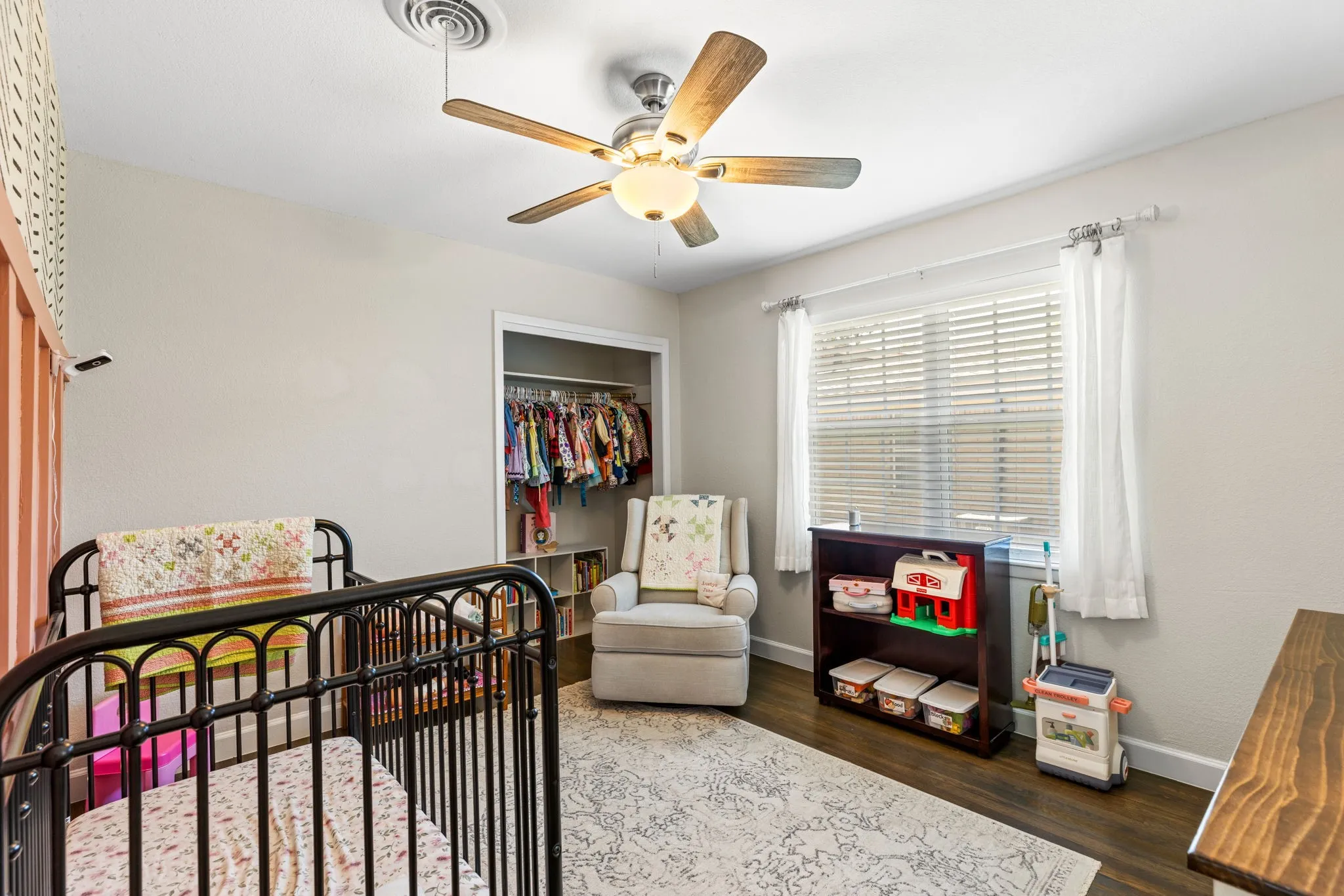 Bedroom with wood-finish flooring, a ceiling fan, and a window with blinds
