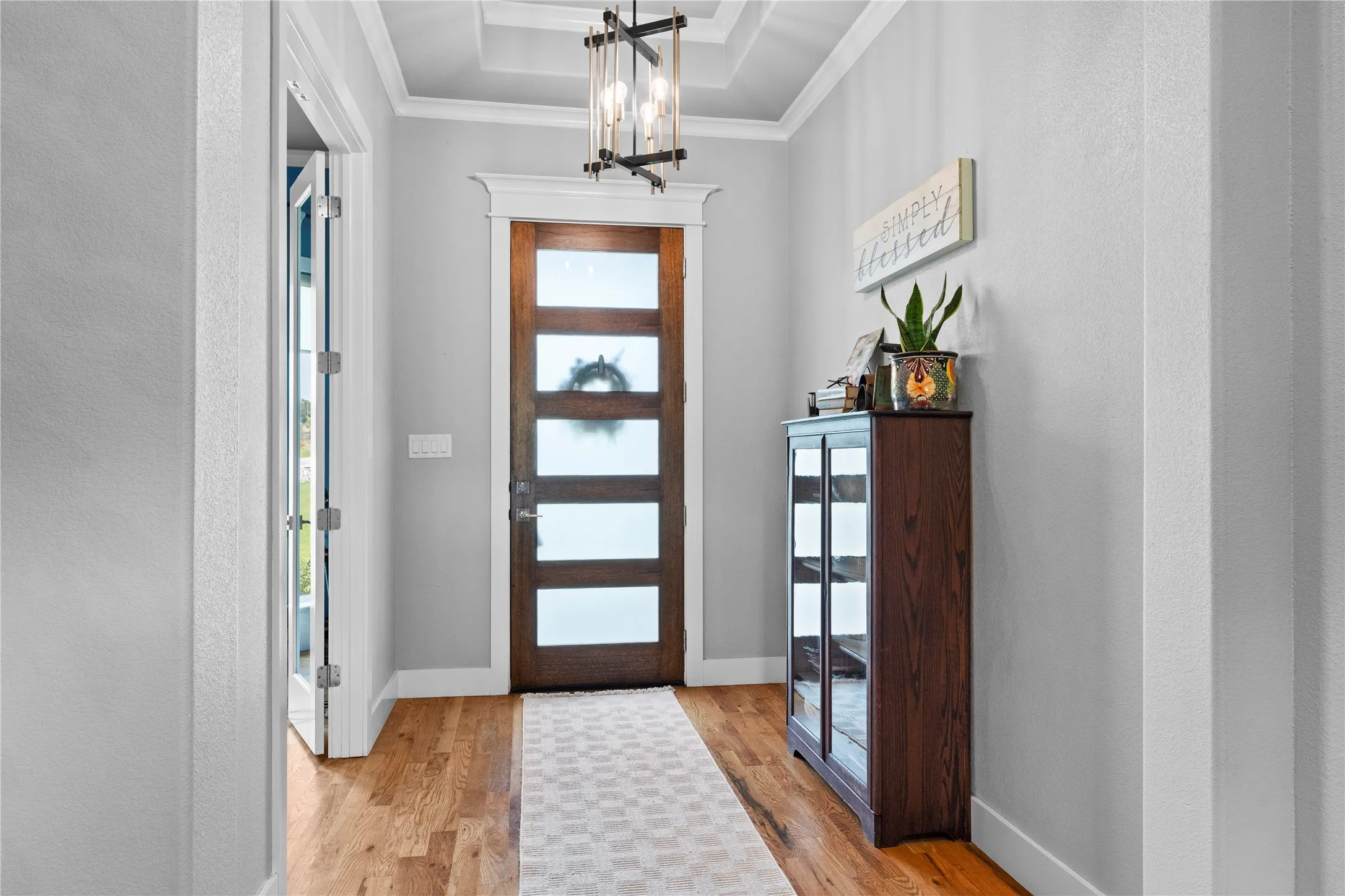 Entryway featuring a wood-panel door with multiple frosted glass panels, wood-finish flooring, and a coffered ceiling