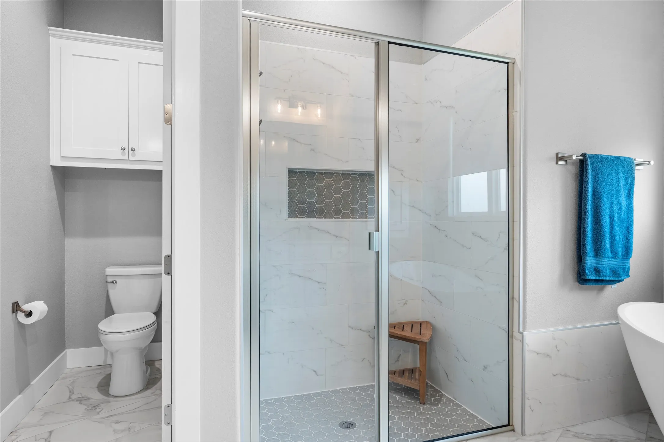 Glass-enclosed shower featuring large format tile surrounds and a hexagonal tile floor