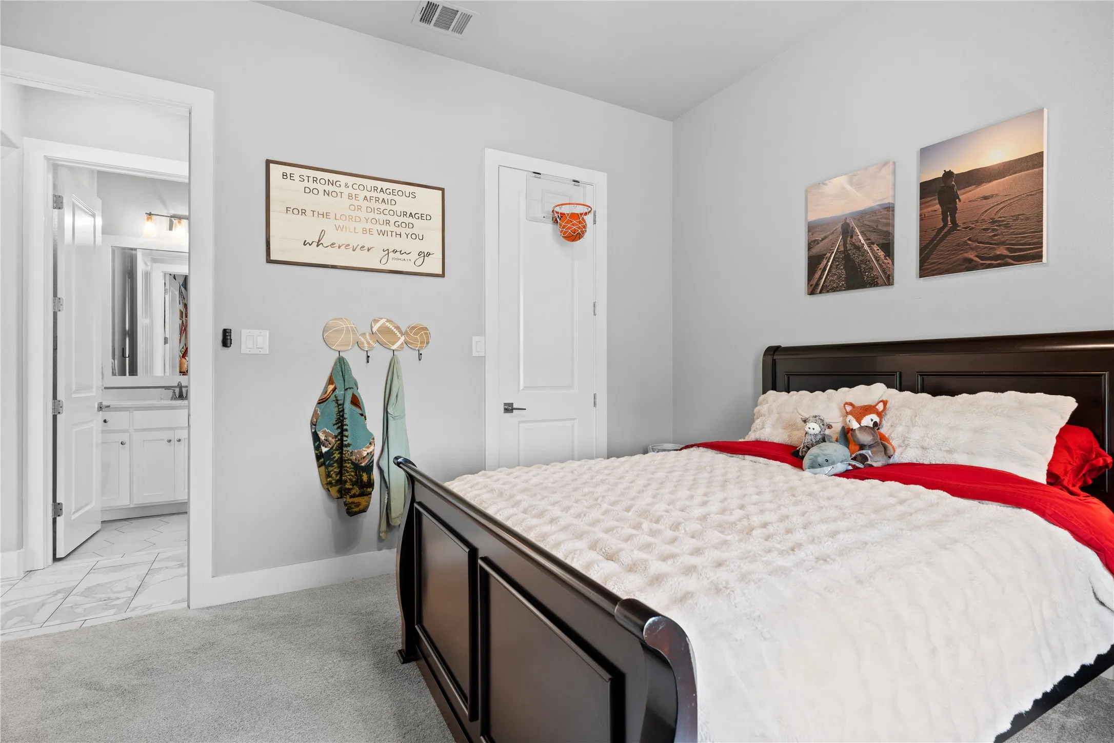 Bedroom featuring light gray walls, carpet flooring, and a dark wood-finish bed frame
