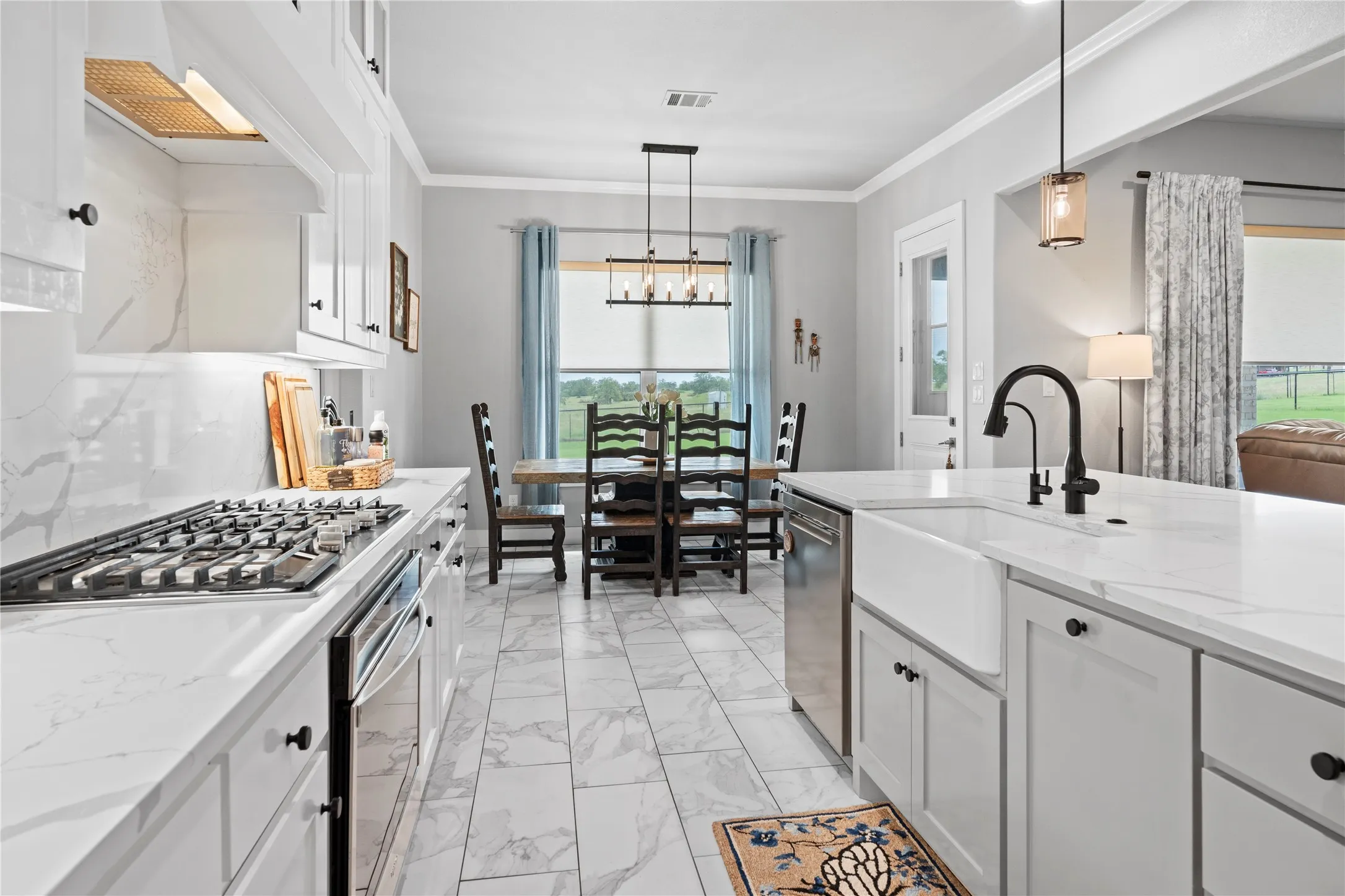 Contemporary kitchen featuring white cabinetry, a gas range with a tile backsplash, white countertops, a large island with an apron-front sink, and matte black fixtures