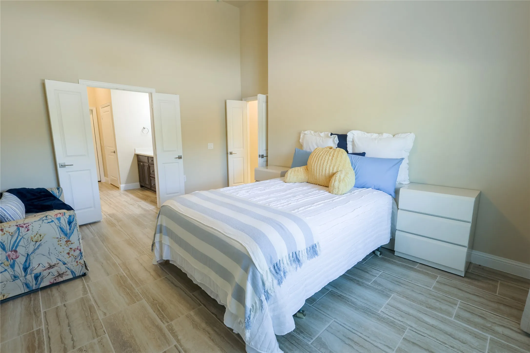 Spacious room featuring light wood-finish plank tile flooring, high ceilings, and neutral wall tones