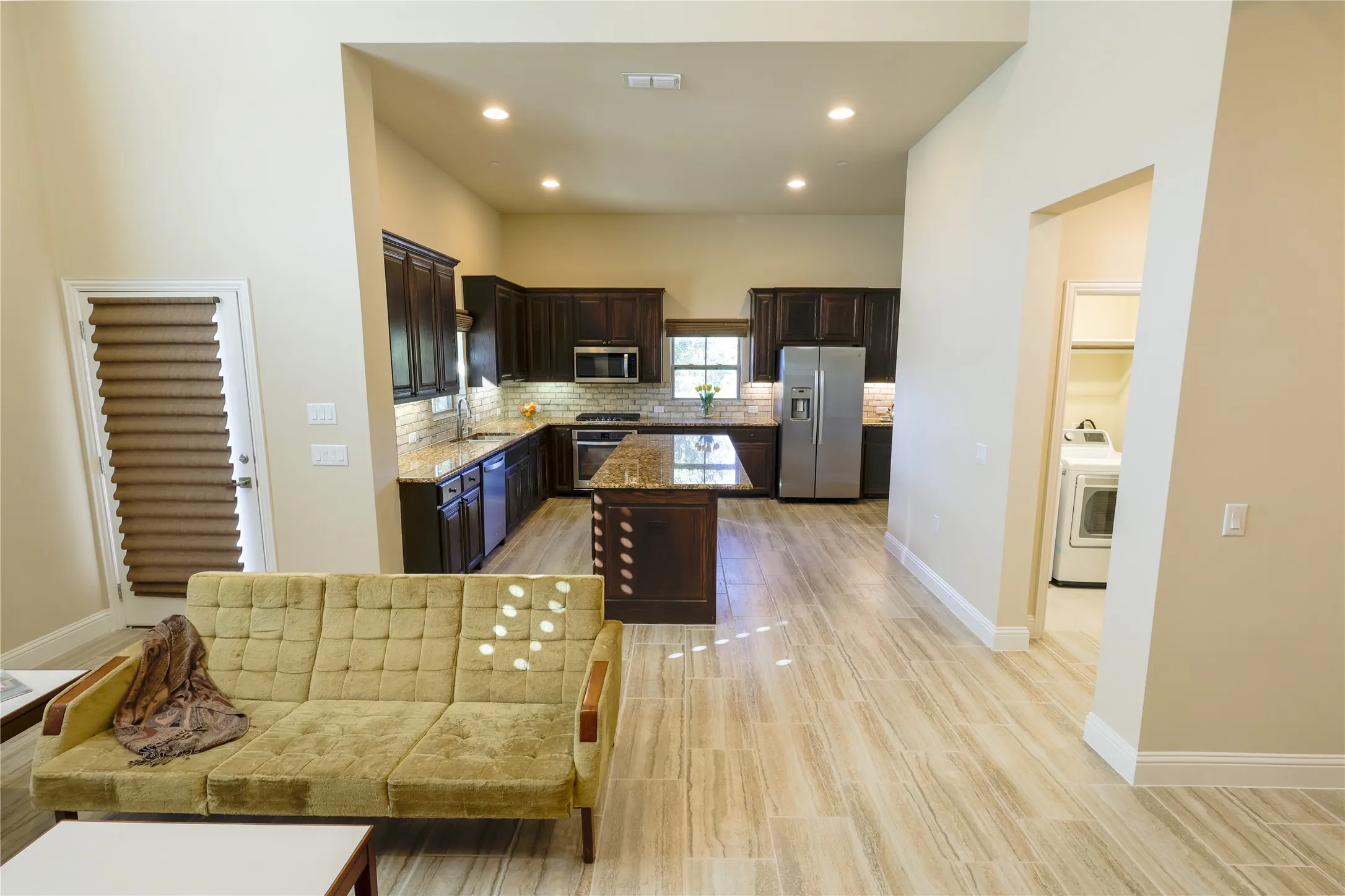 Spacious open-concept living area featuring wood-finish flooring, vaulted ceilings, and recessed lighting