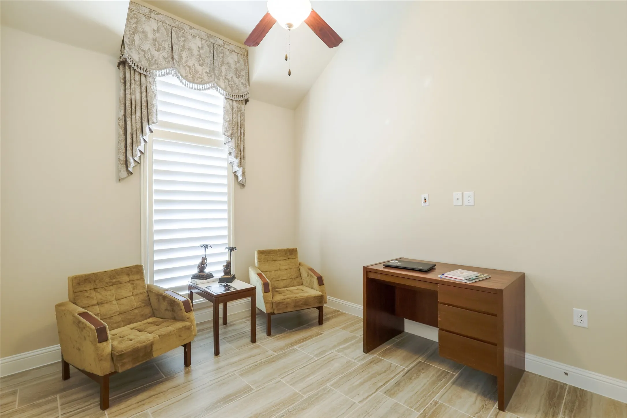 Vaulted ceiling room featuring light-toned wall paint and wood-finish tile flooring