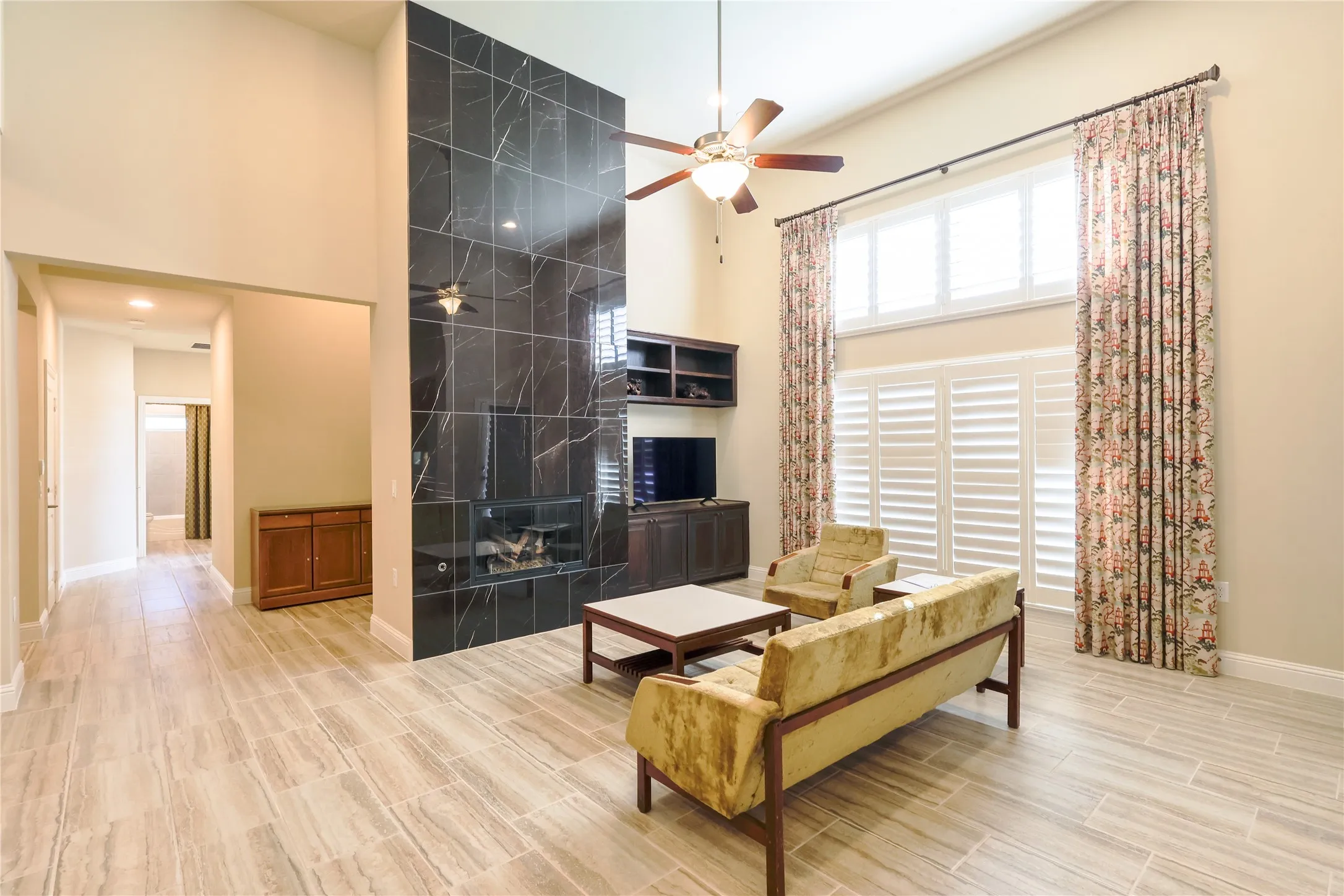 Great room featuring a floor-to-ceiling black tiled fireplace with an integrated firebox, soaring vaulted ceilings, and light wood-finish flooring
