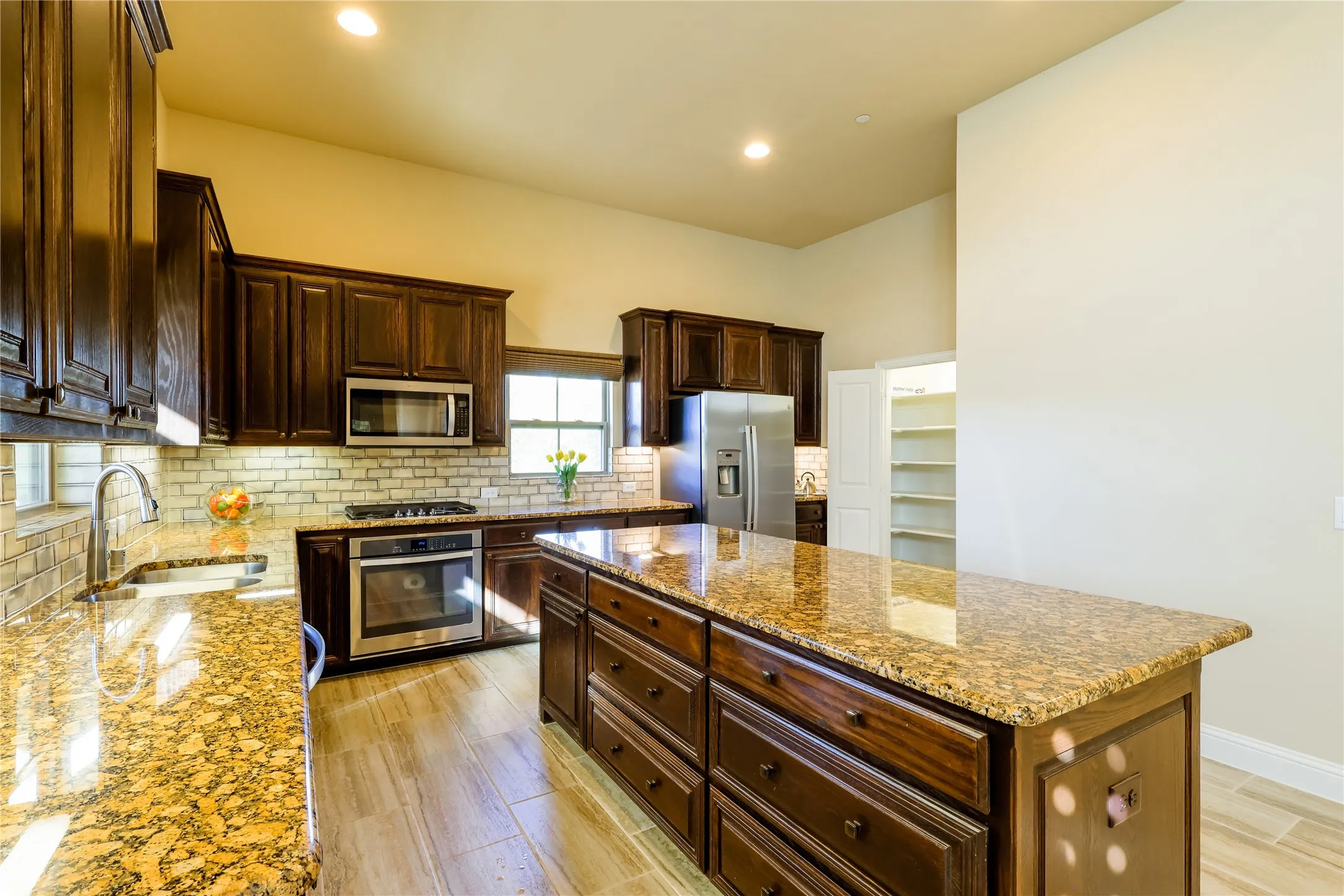 Gourmet kitchen featuring rich wood cabinetry, granite countertops, stainless steel appliances, a tile backsplash, and wood-finish flooring