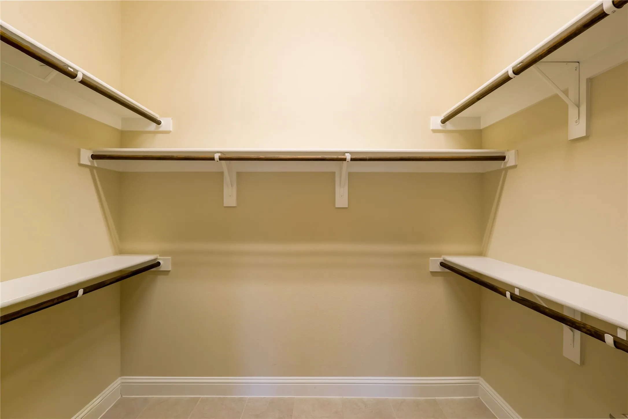 Walk-in closet featuring light beige wall tones and neutral tile flooring