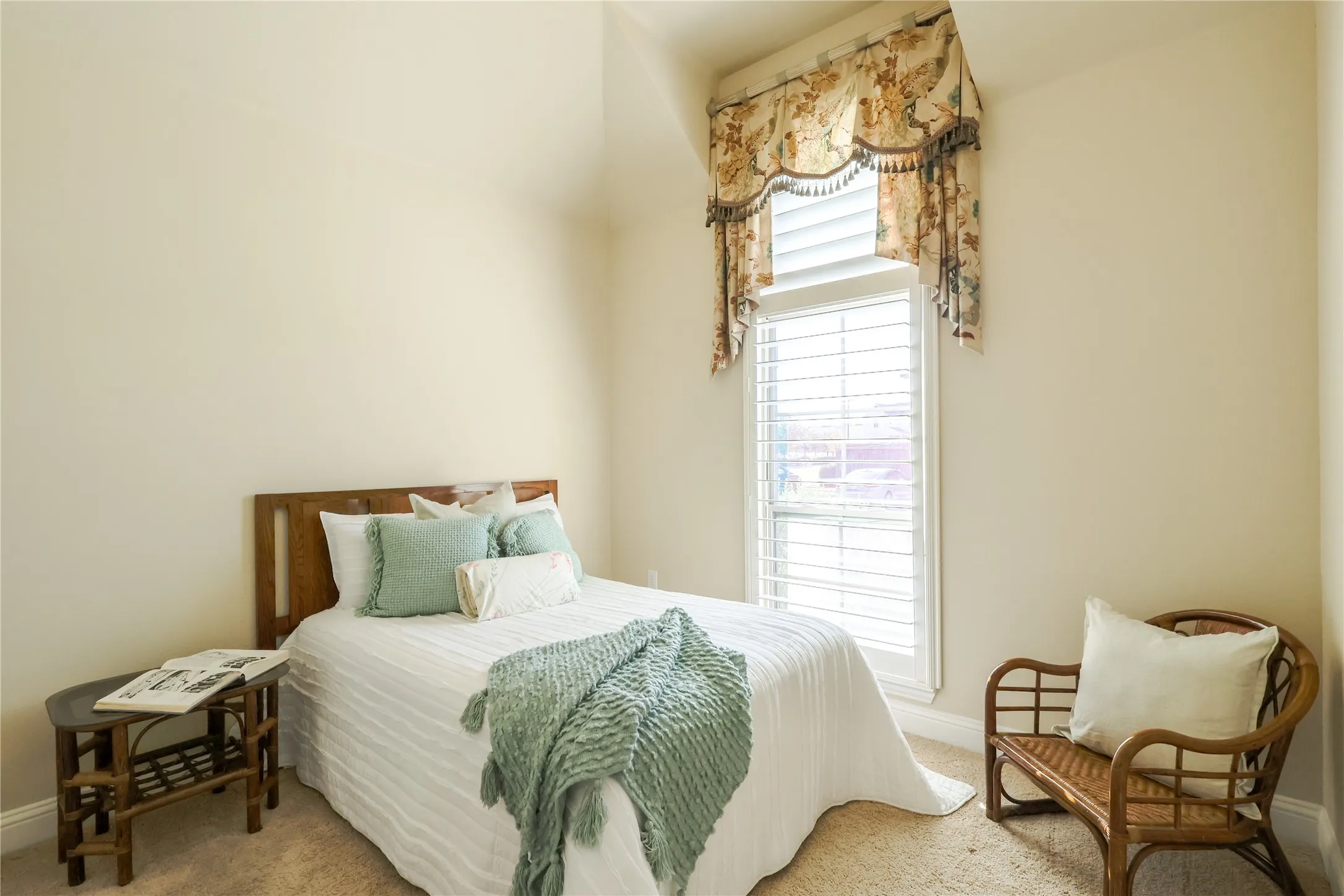 Carpeted room with a wooden headboard, window with plantation shutters, and a sloped ceiling