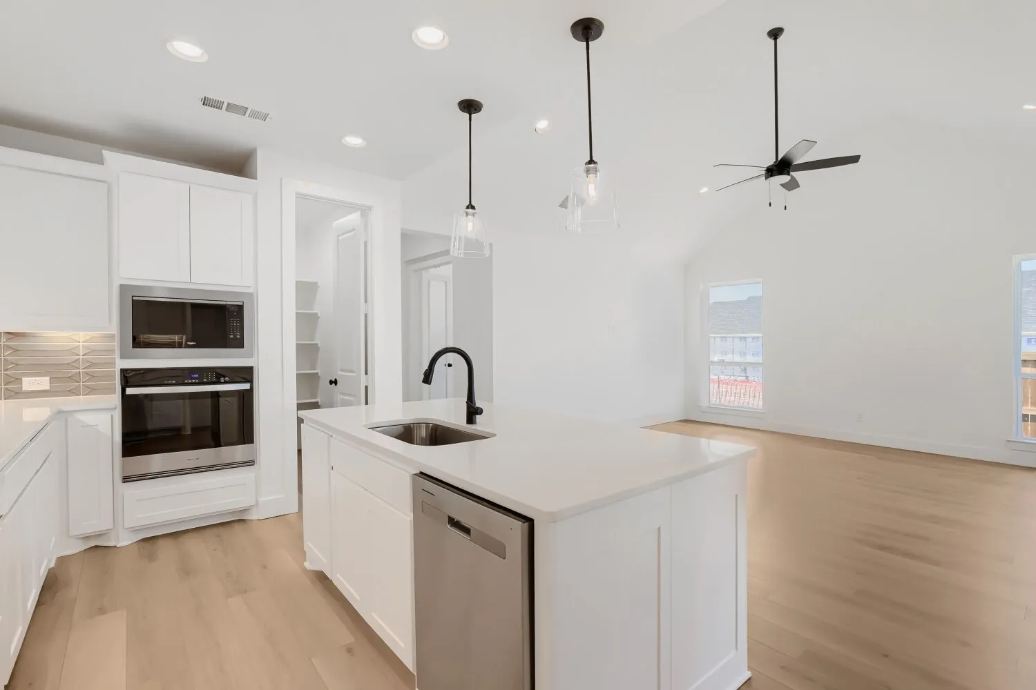 Modern kitchen featuring an island with a stainless steel sink, integrated dishwasher, and pendant lighting