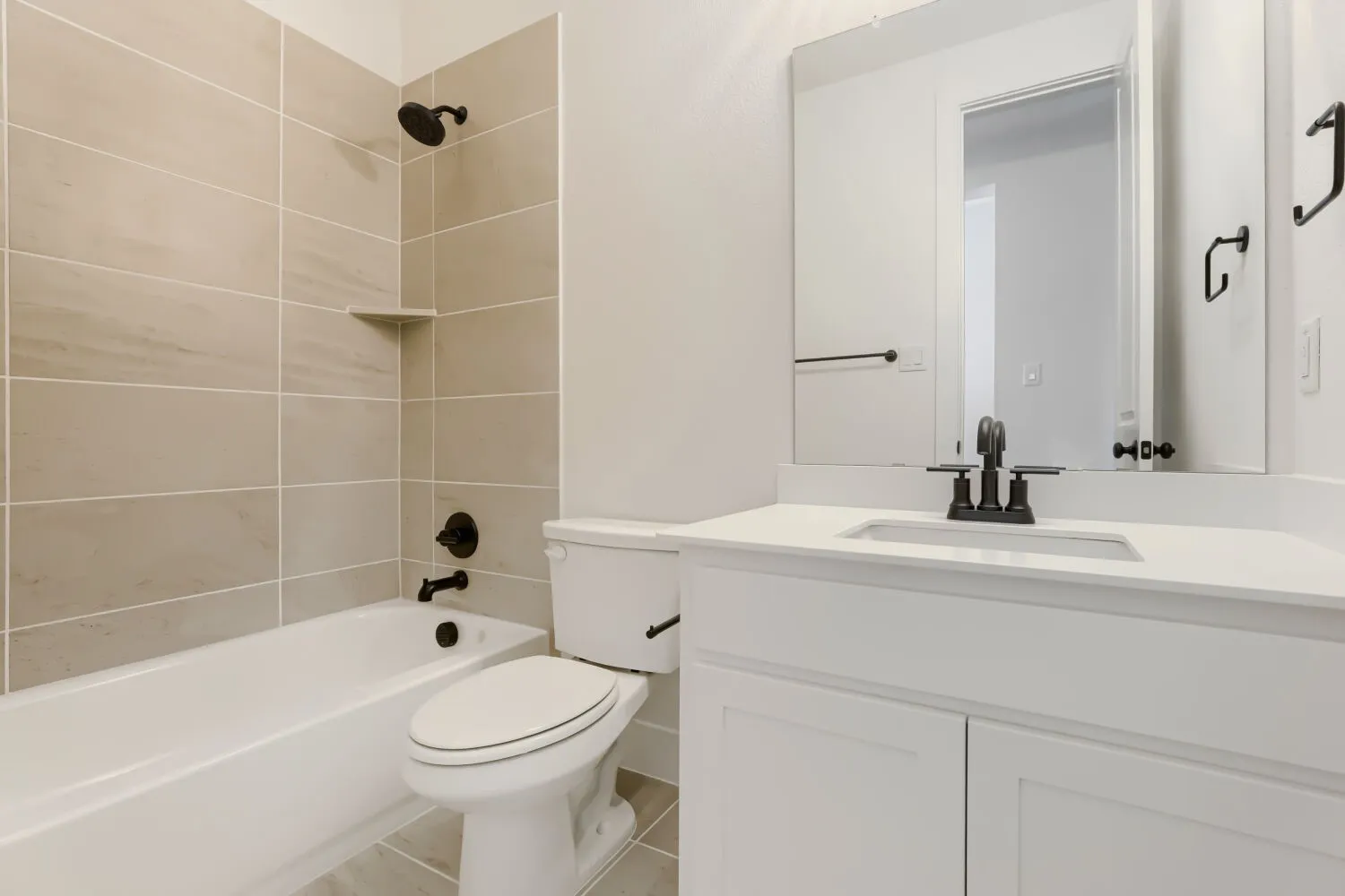Bathroom featuring a tub/shower combination with tiled surround, a white vanity with an undermount sink, and a framed mirror