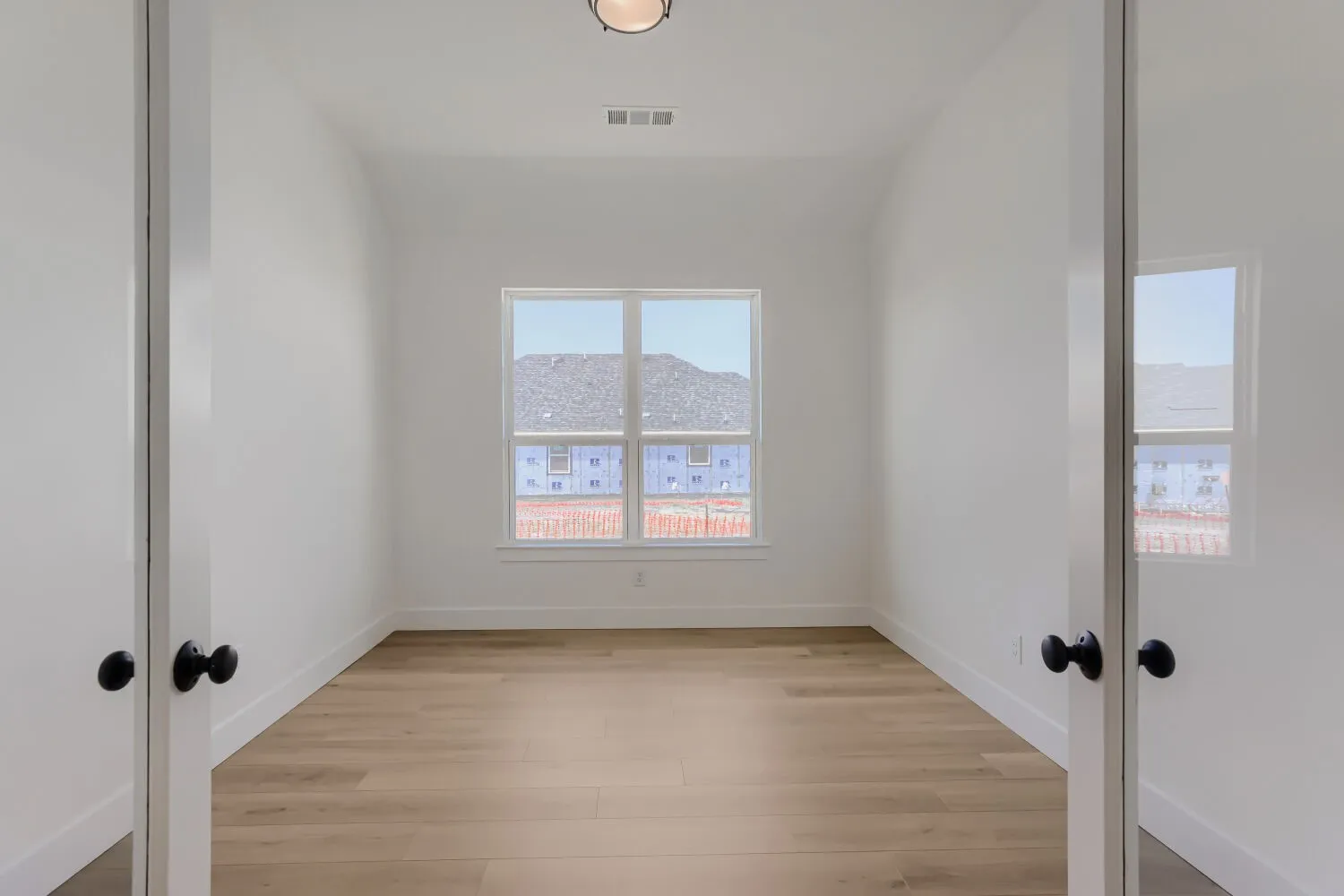 Wood-finish flooring, white walls, white trim, and a ceiling-mounted light fixture
