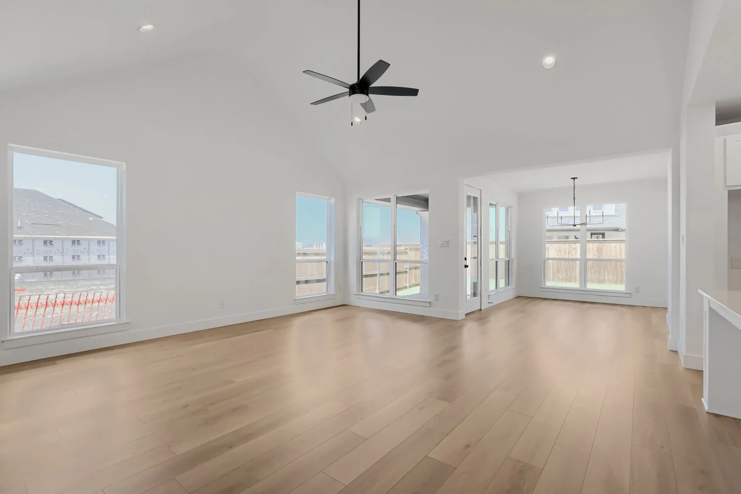 Vaulted ceiling with recessed lighting and a ceiling fan, wood-finish flooring, and multiple windows