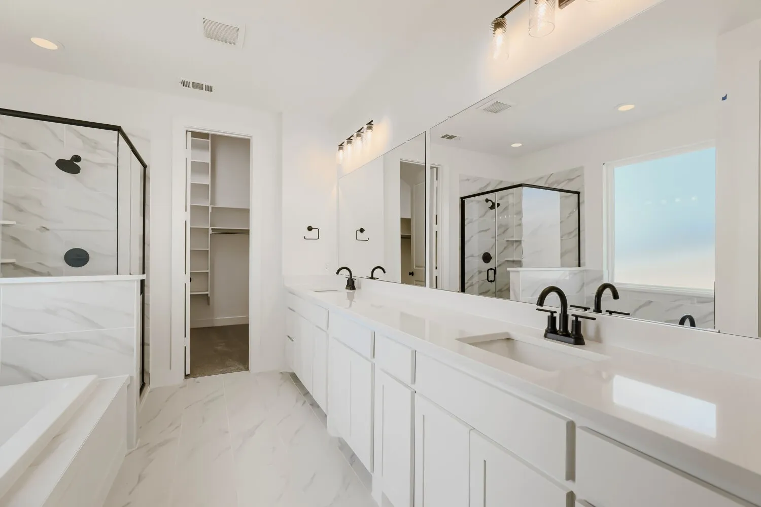 Dual vanity with undermount sinks, white cabinetry, and a continuous mirror