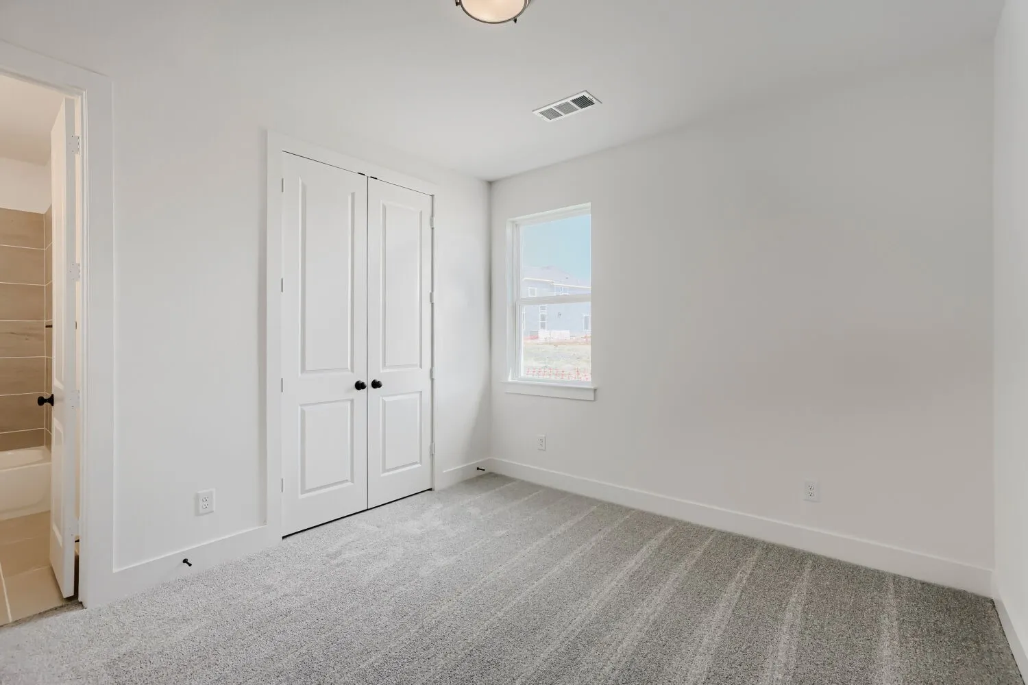 Light gray wall-to-wall carpeting, white walls, and a window with white trim