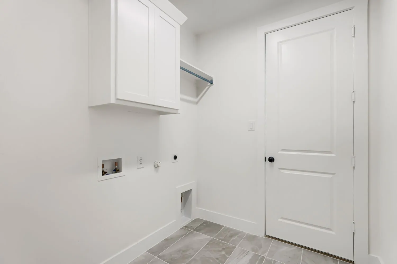 White shaker-style cabinetry, a built-in hanging rod, and a paneled interior door with matte black hardware
